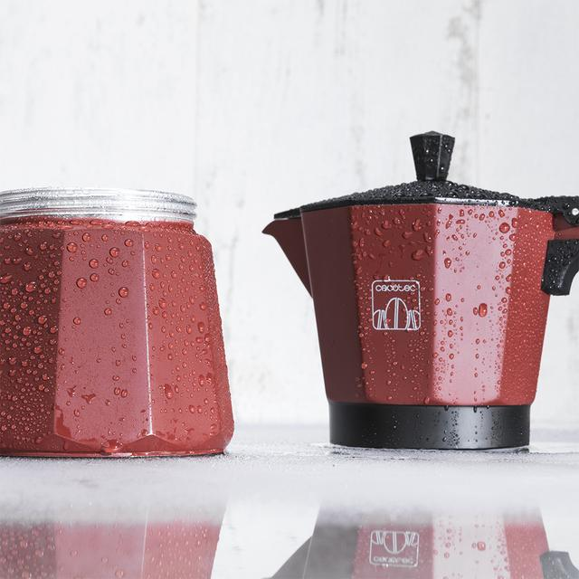 Cafetera roja y frasco de vidrio con gotas de agua. Superficie reflectante. Fondo blanco. Marca Cecotec visible.