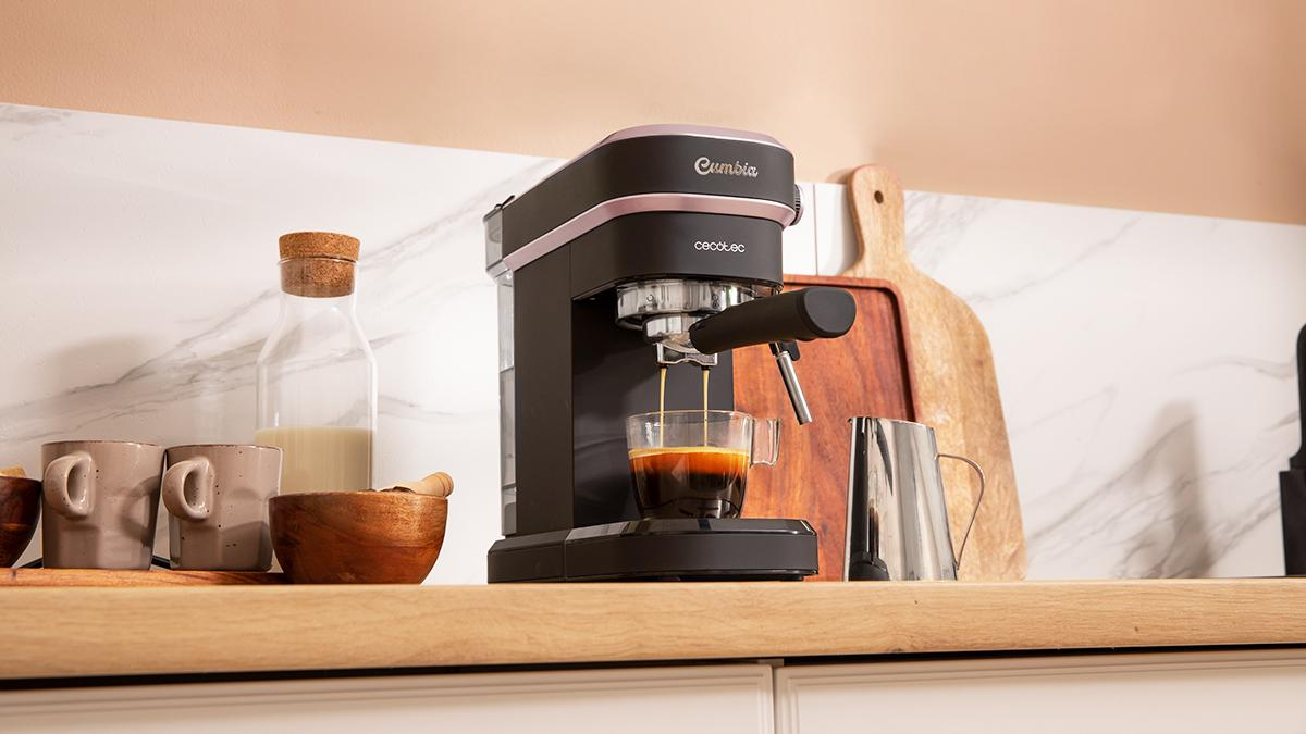Máquina de espresso vertiendo café en un vaso. Tazas, botella de leche y tablas de cortar en una estantería de madera.