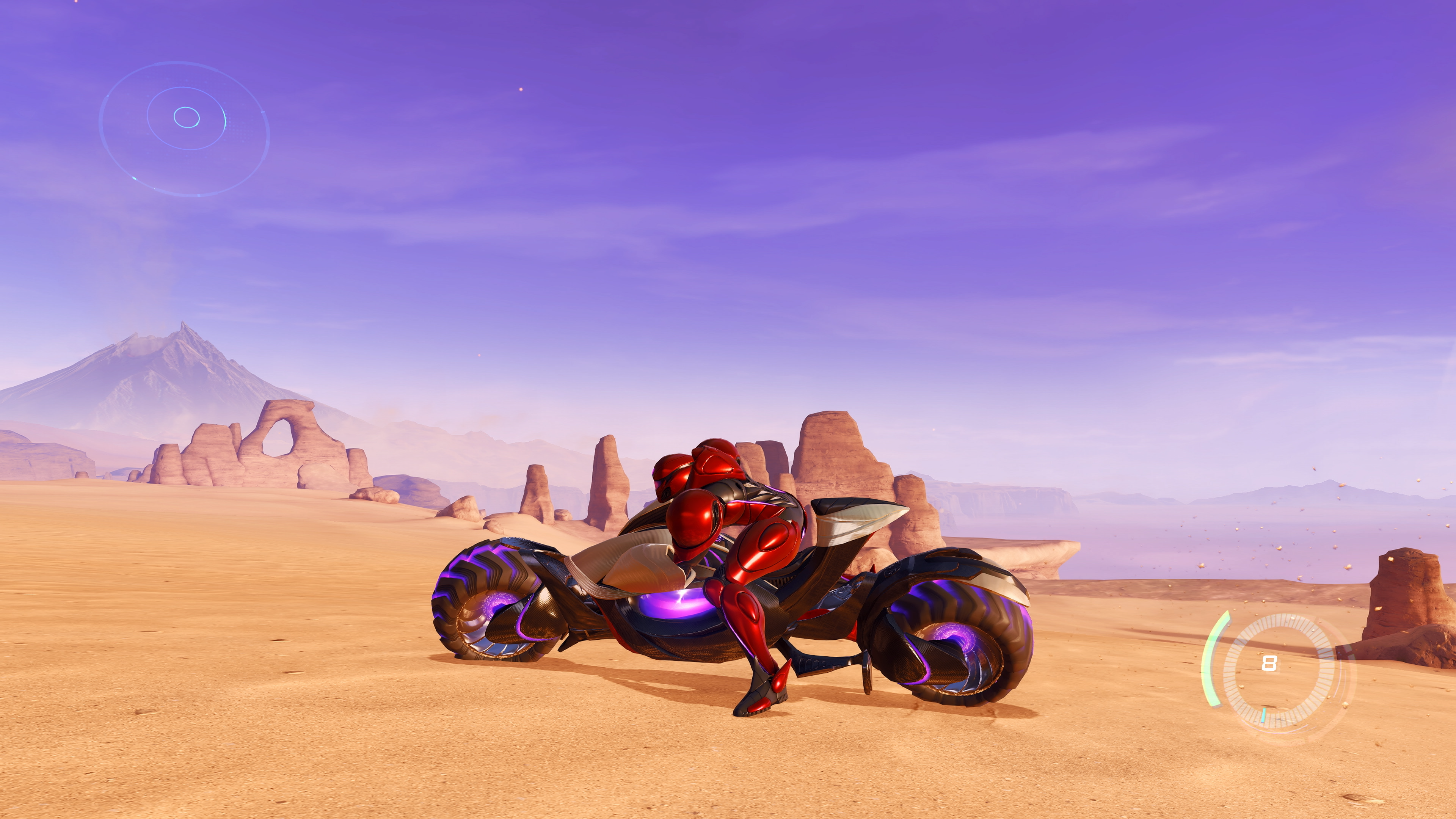 Una figura vestida de rojo se sienta en una motocicleta futurista en un paisaje desértico. Cielo púrpura, formaciones rocosas y una pantalla son visibles.