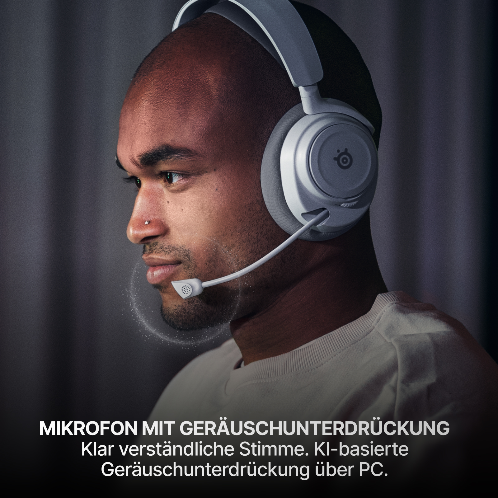 Ein Mann mit weißen Kopfhörern und Mikrofon. Die Kopfhörer sind auf seinem Kopf. Der Hintergrund ist dunkelgrau.