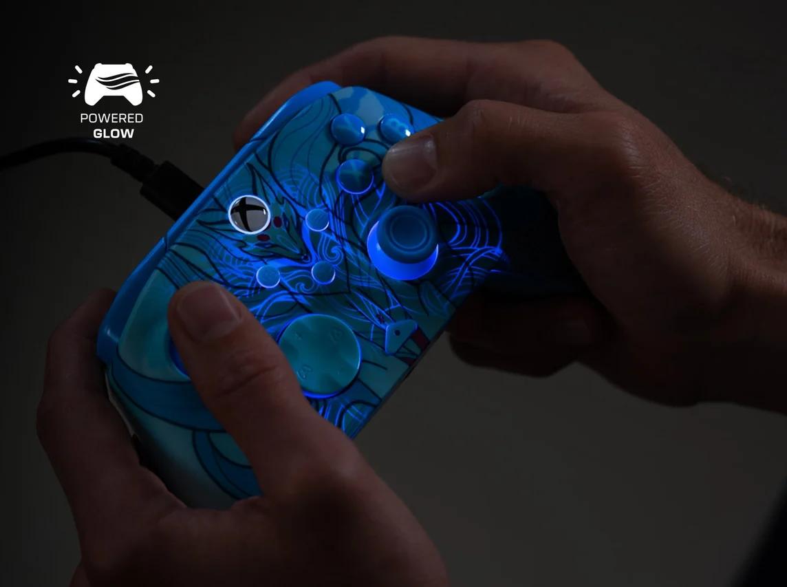 Hände halten einen blau leuchtenden Gamecontroller. Er hat ein Design mit leuchtenden Mustern. Die Knöpfe und das Logo leuchten ebenfalls.