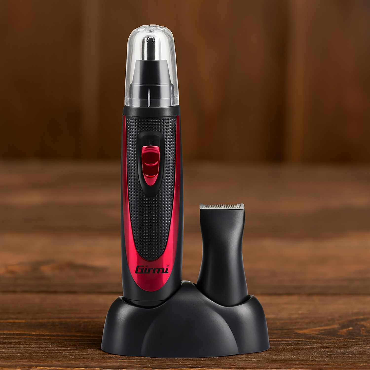 Un tagliacapelli per naso nero e rosso e la sua base, su una superficie di legno. Il tagliacapelli ha un cappuccio di plastica trasparente e un pulsante rosso.