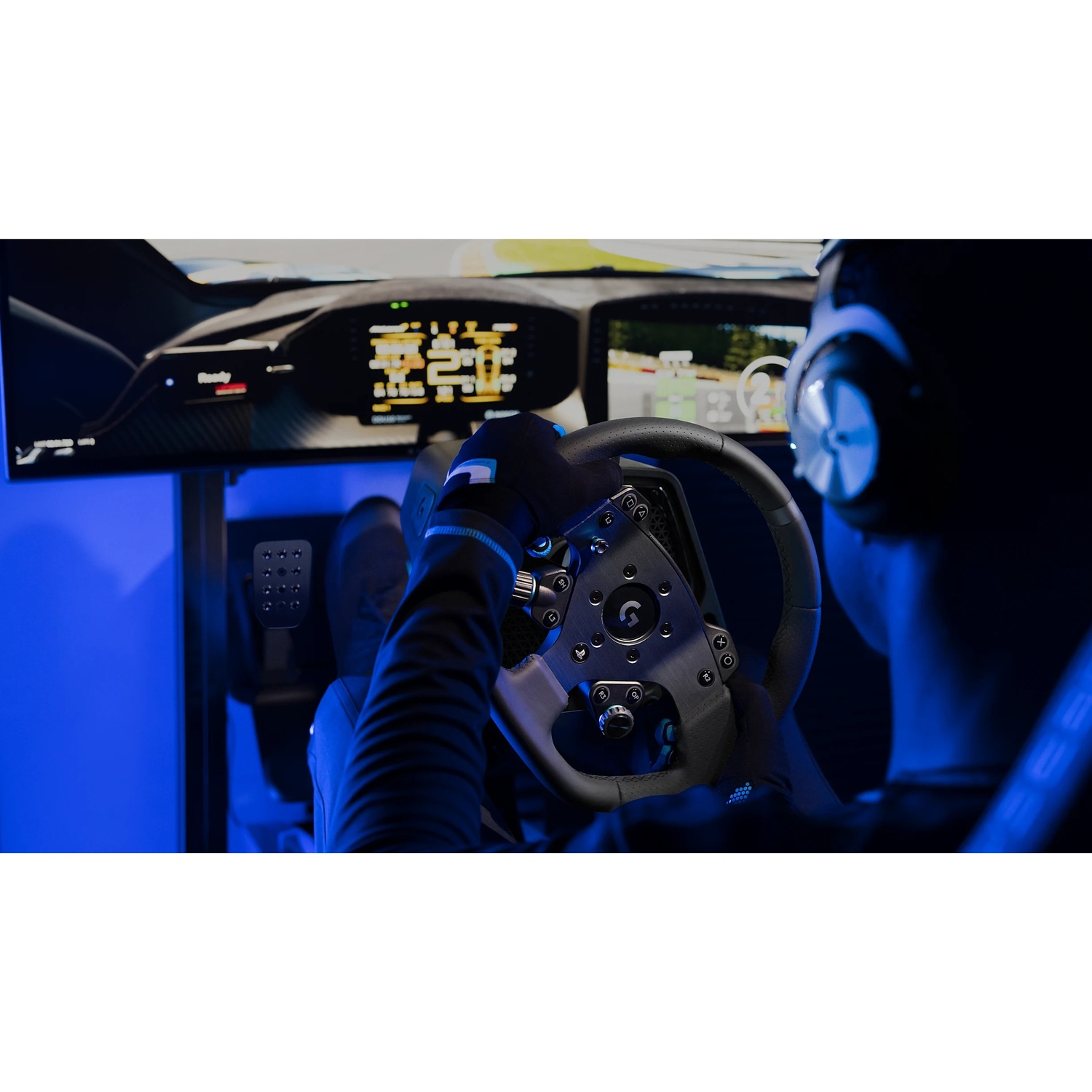 Una persona con guanti e cuffie usa un simulatore di corse. Si vede un volante, con schermi che mostrano un gioco di corse.
