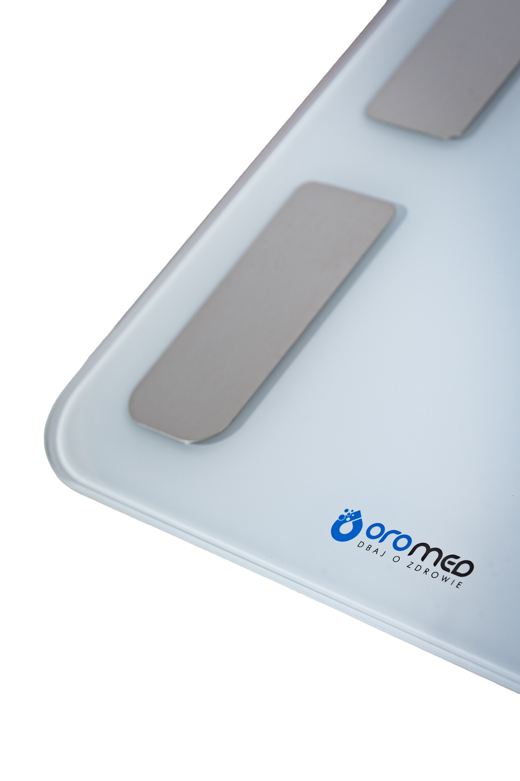Biała waga cyfrowa z trzema srebrnymi podkładkami. Nazwa marki 'oromed' jest w kolorze niebieskim. Tło jest białe.