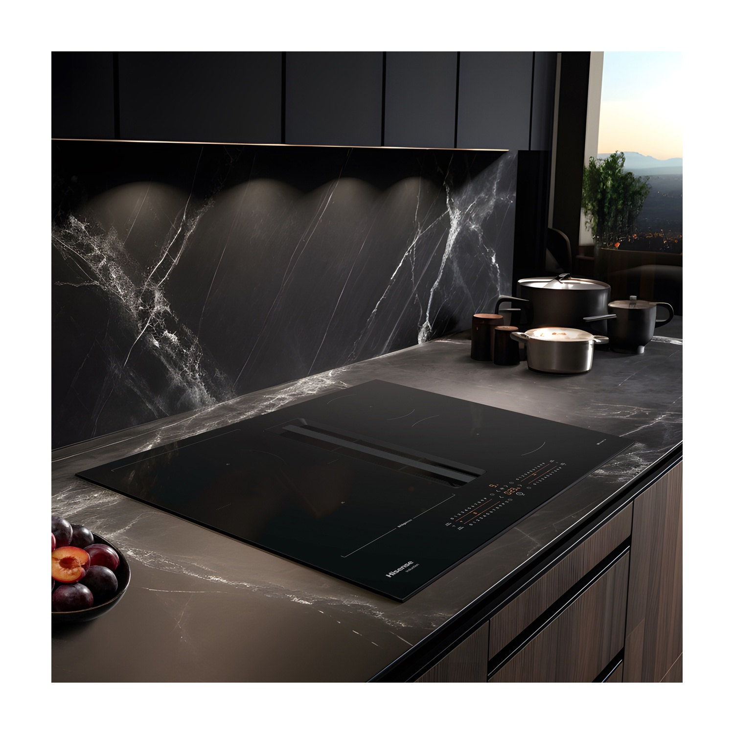Cucina moderna con piano cottura nero, pentole e una ciotola di prugne. Sfondo con paraschizzi in marmo e paesaggio urbano.