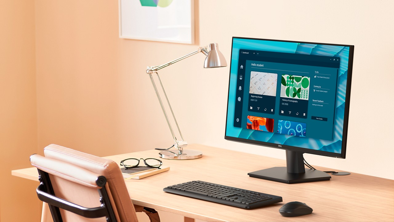 Ein Schreibtisch mit Monitor, Tastatur, Maus, Lampe, Stuhl und Brille.
