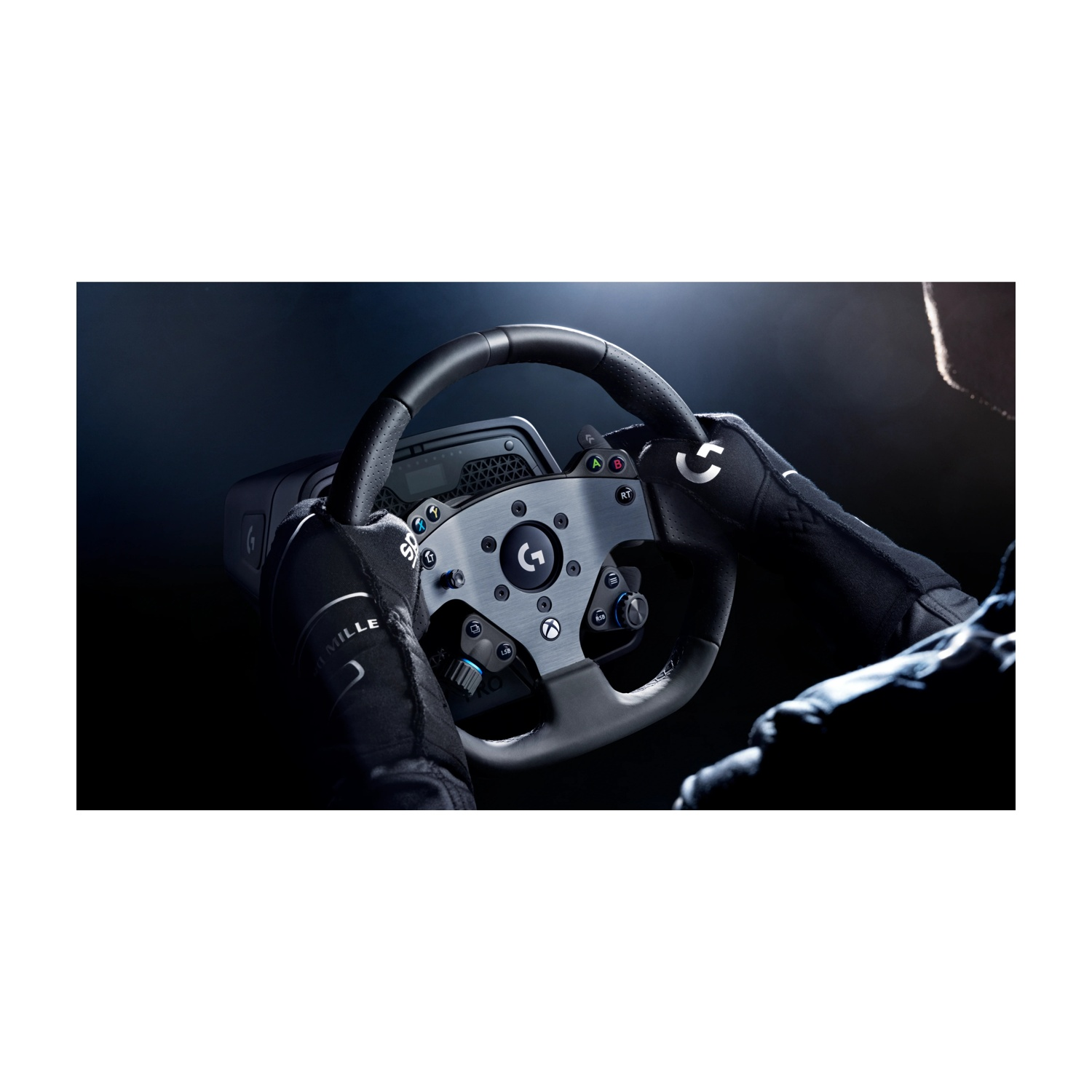 Mani con guanti neri che tengono un volante da corsa Logitech con dettagli argentati. Sfondo scuro con uno scorcio della silhouette del pilota.