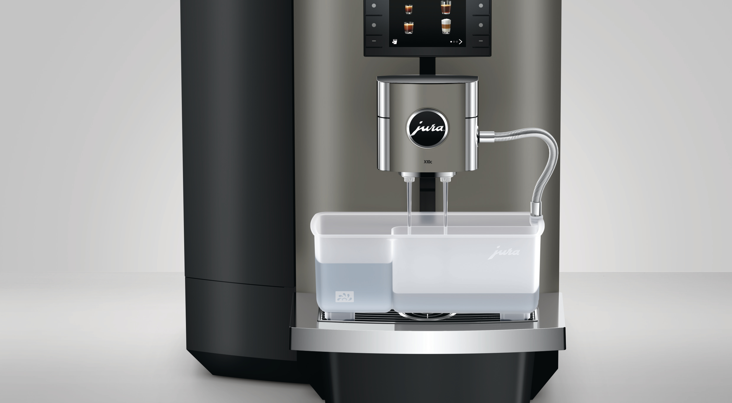 Eine silberne Jura-Kaffeemaschine mit Wassertank. Ein Bildschirm zeigt Kaffeeoptionen an. Ein flexibler Schlauch und Wasserauslässe sind sichtbar.