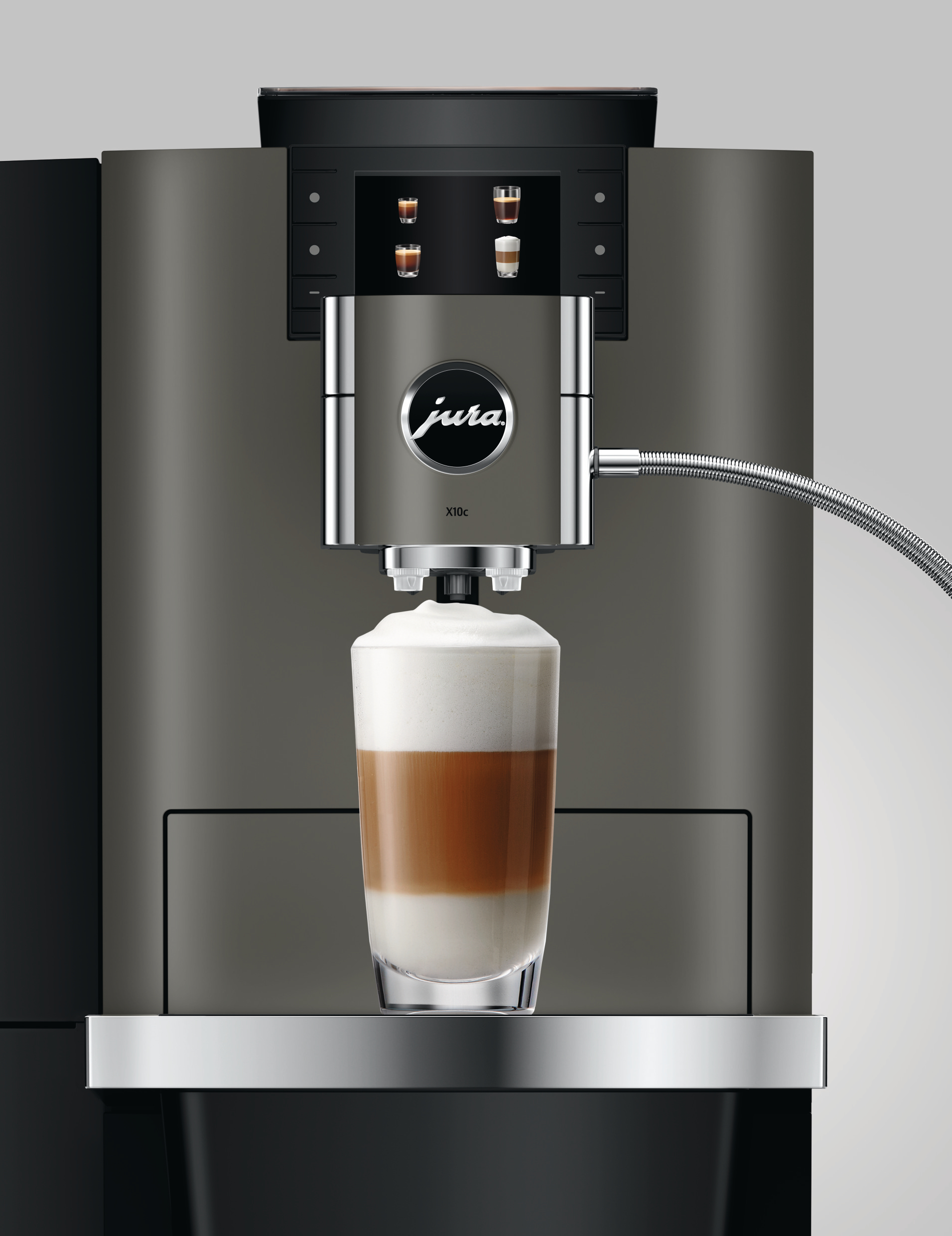 Eine Kaffeemaschine mit einem Glas Latte Macchiato. Die Maschine ist grau mit einem Chromauslauf. Das Getränk hat Schichten.