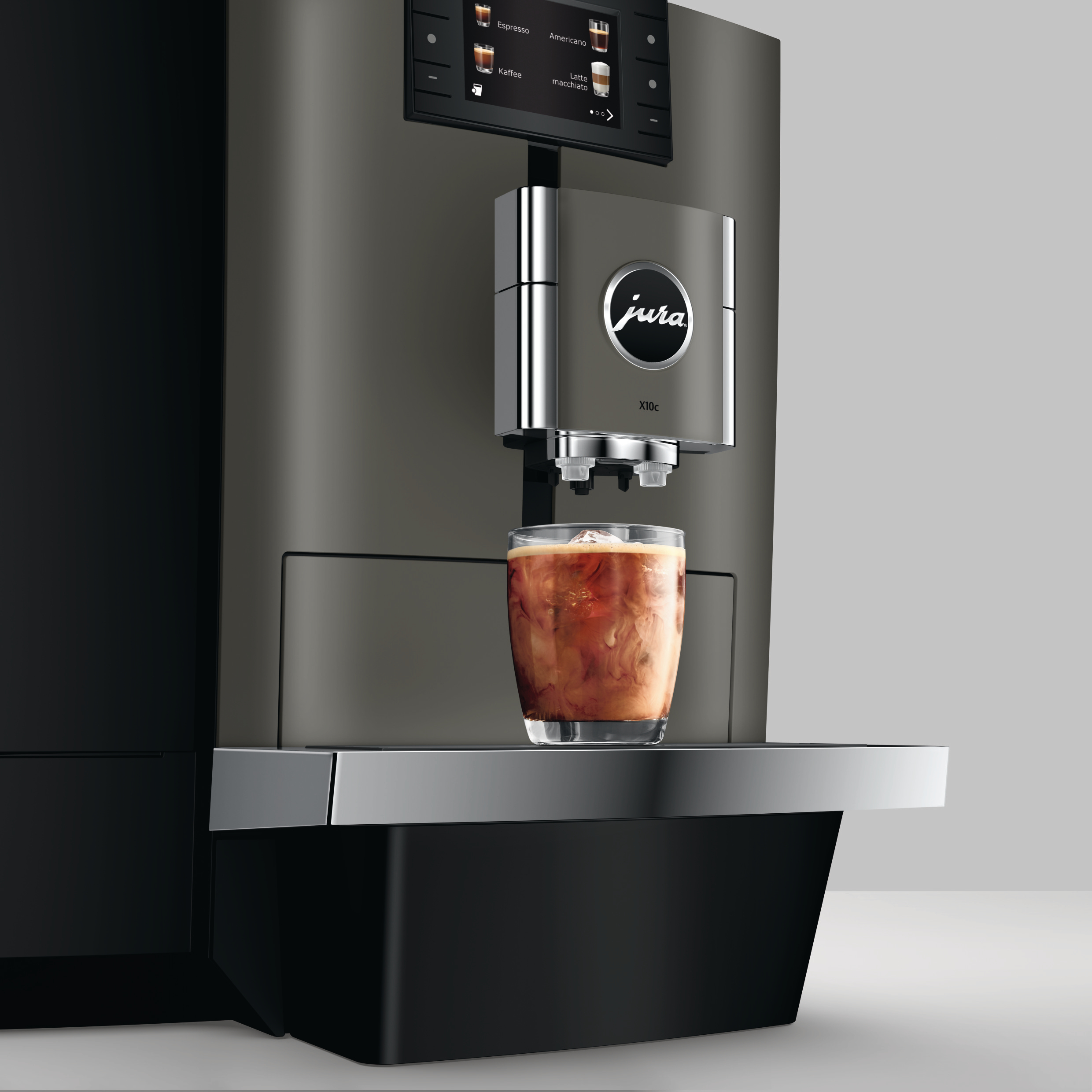 Eine Kaffeemaschine gibt ein Getränk in ein Glas aus. Die Maschine ist grau und das Getränk braun mit Eis.