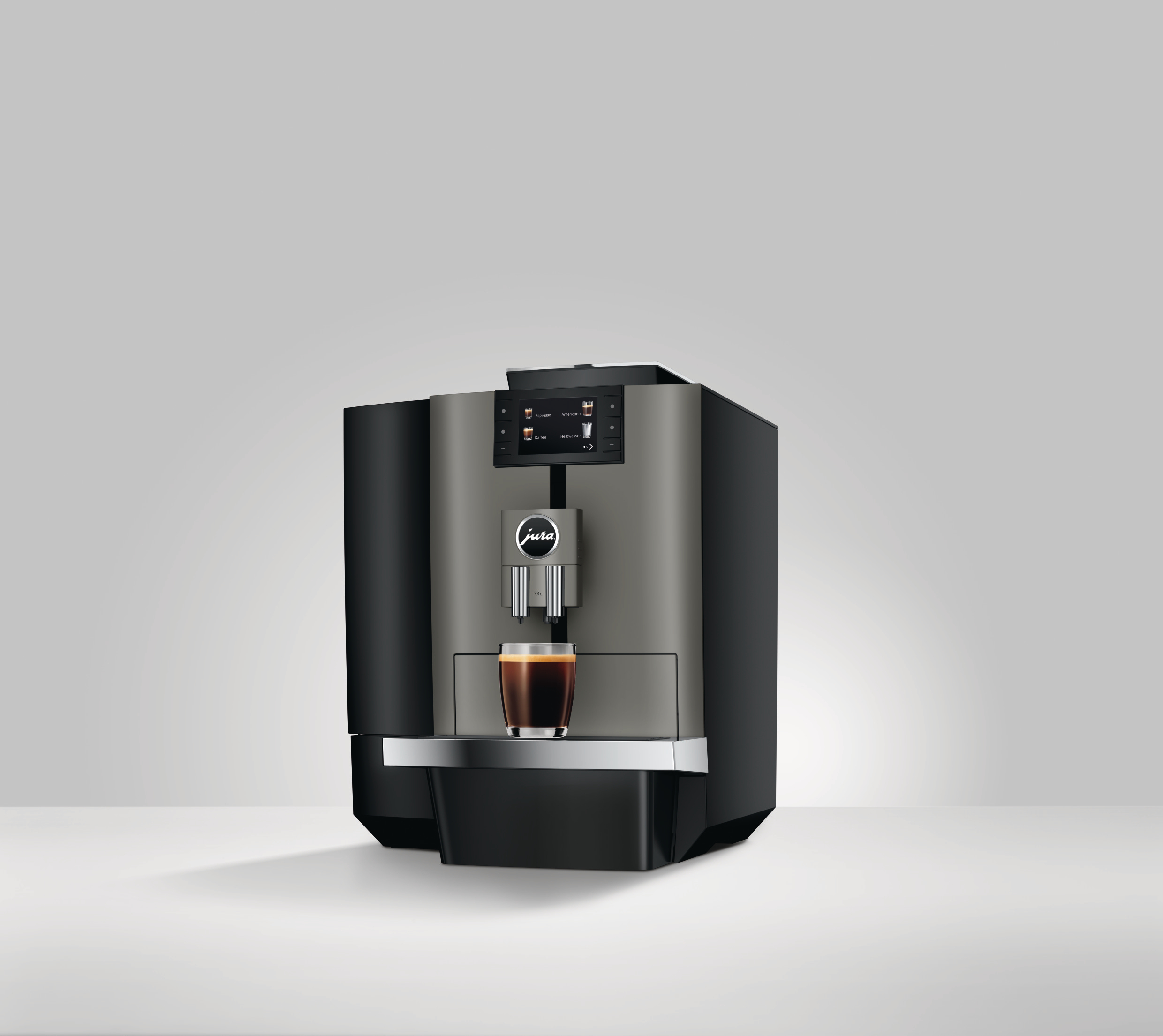 Eine Kaffeemaschine mit einem Glas Kaffee. Die Maschine ist grau und schwarz. Sie steht auf einer weißen Oberfläche.