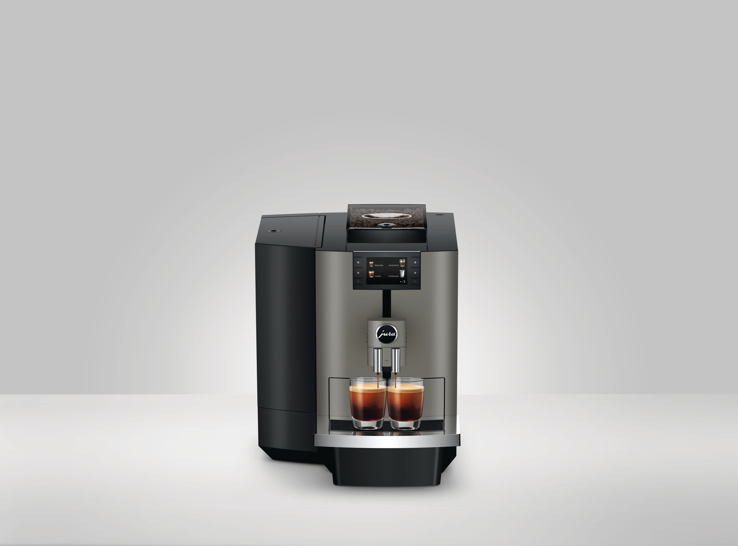 Eine Kaffeemaschine gibt Espresso in zwei Gläser aus. Die Maschine ist silber und schwarz, mit einem Bildschirm und dem Jura-Logo.