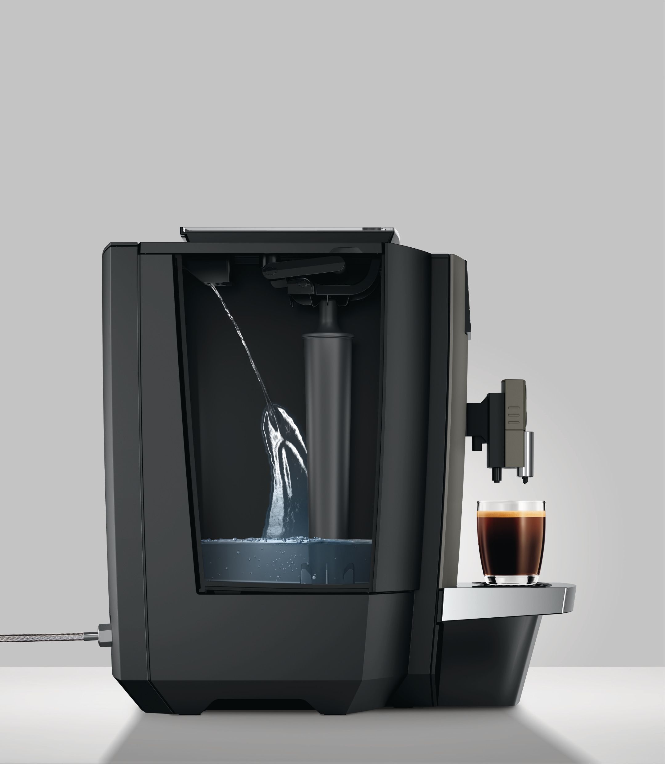 Kaffeemaschine mit Wasser. Eine Tasse Kaffee rechts. Grauer Hintergrund.
