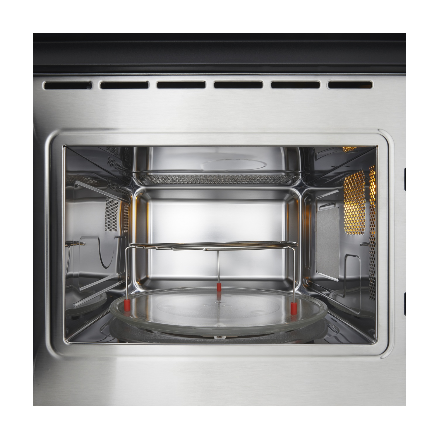 All'interno di un forno a microonde in acciaio inossidabile. Un piatto di vetro e una griglia metallica sono all'interno. La luce è accesa, illuminando l'interno.