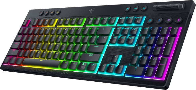 Una tastiera Razer nera con tasti retroilluminati, che mostra colori arcobaleno. Dispone di controlli multimediali e una rotella del volume.