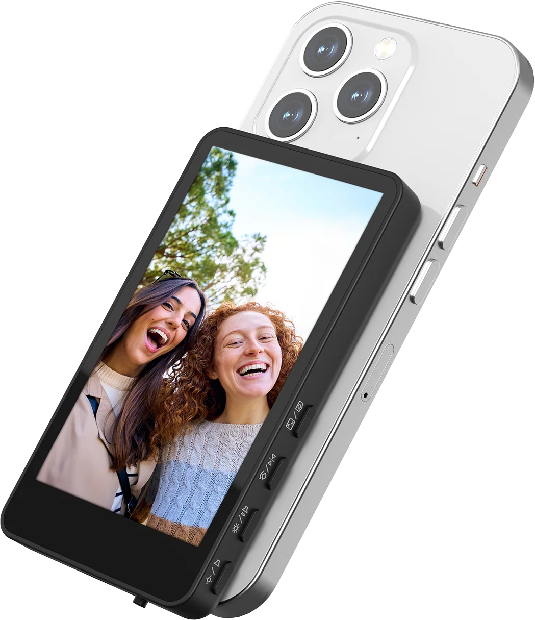 Zwei lachende Frauen auf einem Gerät mit einem Telefon dahinter. Das Telefon hat Kameras und einen silbernen Rahmen.