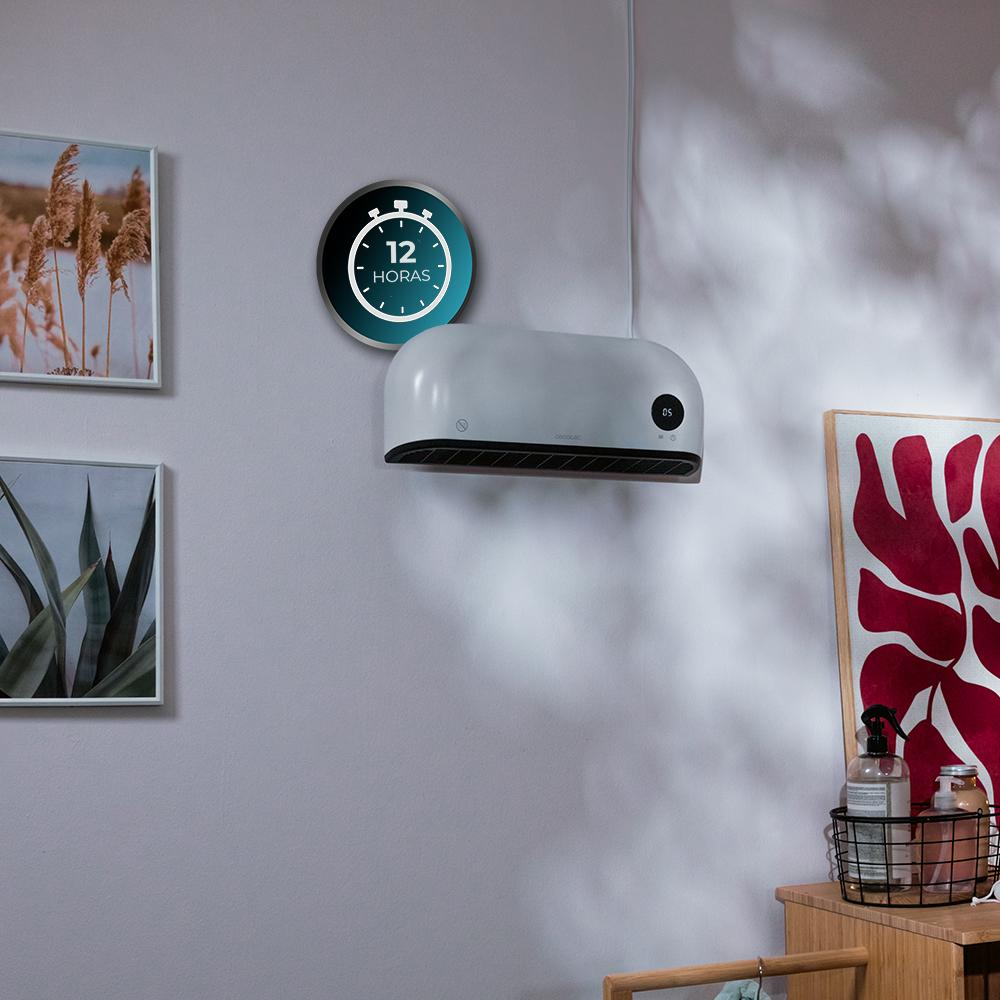 Un purificador de aire blanco en una pared, con una pantalla de temporizador. Obras de arte y una cesta con objetos en una superficie de madera.