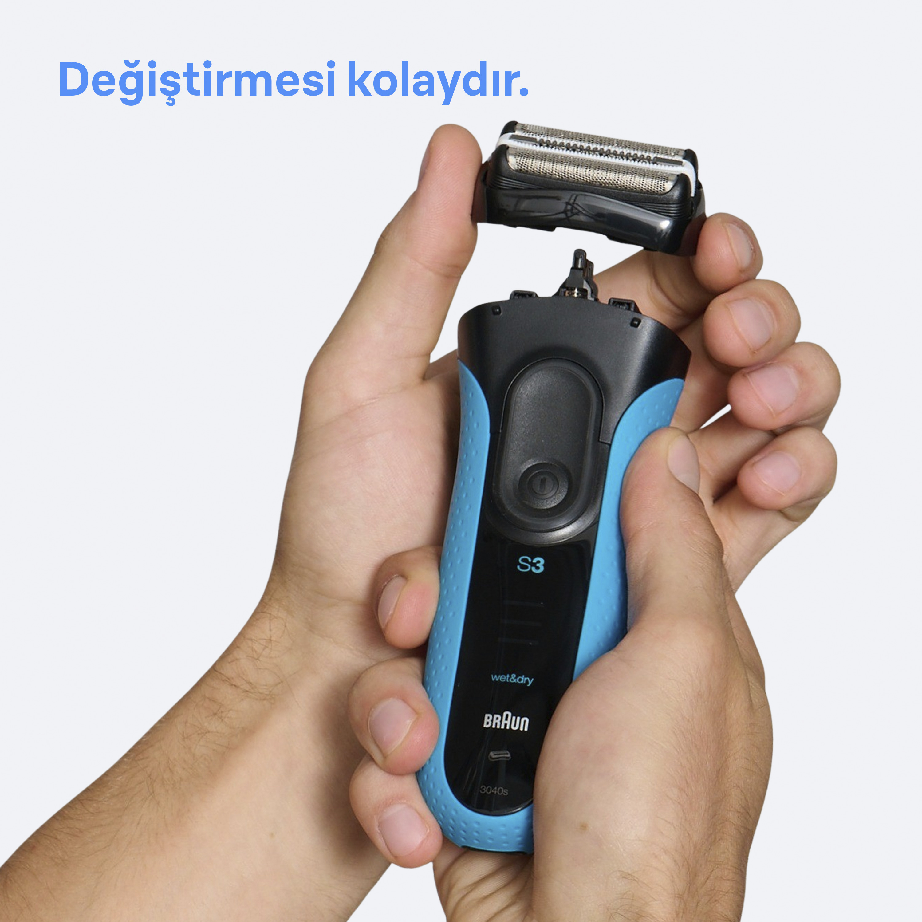 Eller, başlığı çıkarılmış, mavi ve siyah bir elektrikli tıraş makinesi tutuyor.