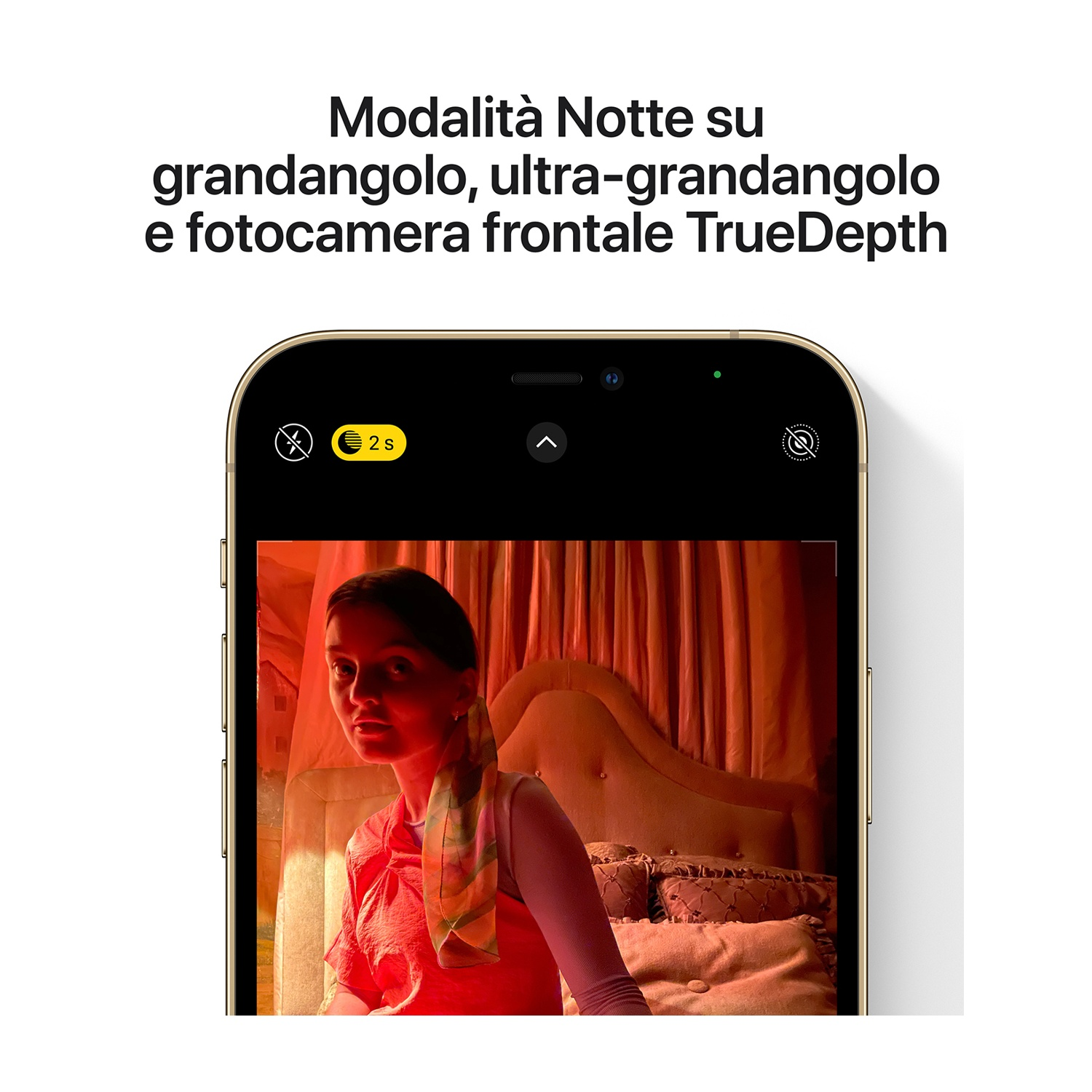Un telefono mostra una donna in una stanza illuminata di rosso. Lo schermo mostra le impostazioni della modalità notturna. Il testo recita 'Modalità notte su grandangolo, ultra-grandangolo e fotocamera frontale TrueDepth'.