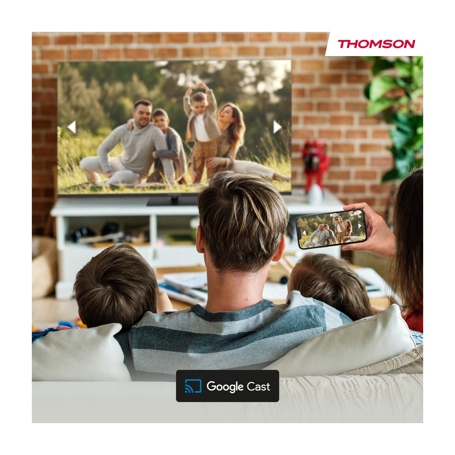 Famiglia che guarda la TV, telefono che mostra la stessa immagine. La TV mostra la famiglia all'aperto. Le persone sono sedute su un divano.