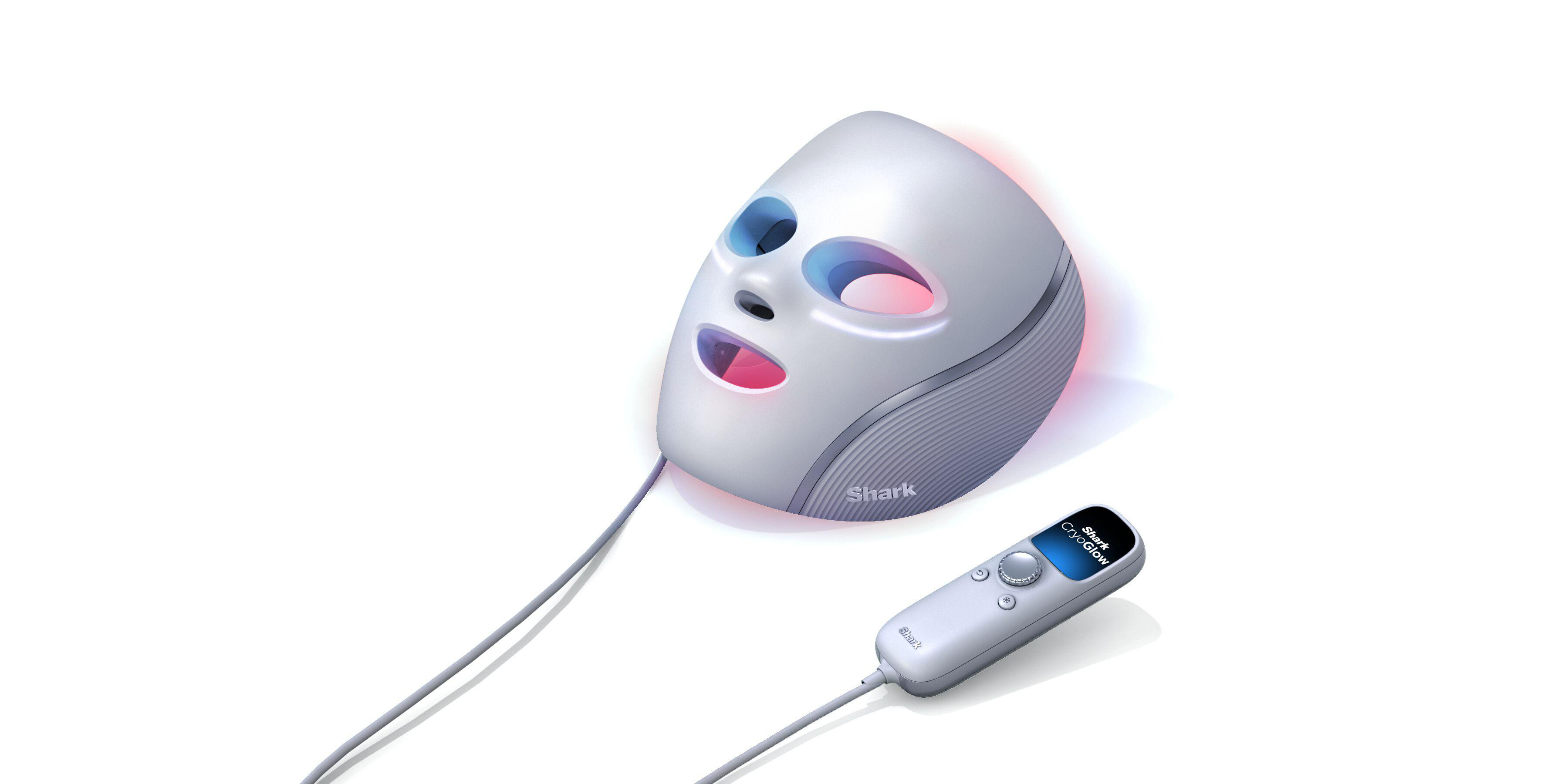 Eine weiße Shark CryoGlow Gesichtsmaske mit angeschlossenem Controller liegt auf einer weißen Oberfläche. Die Maske hat Augen- und Mundlöcher.