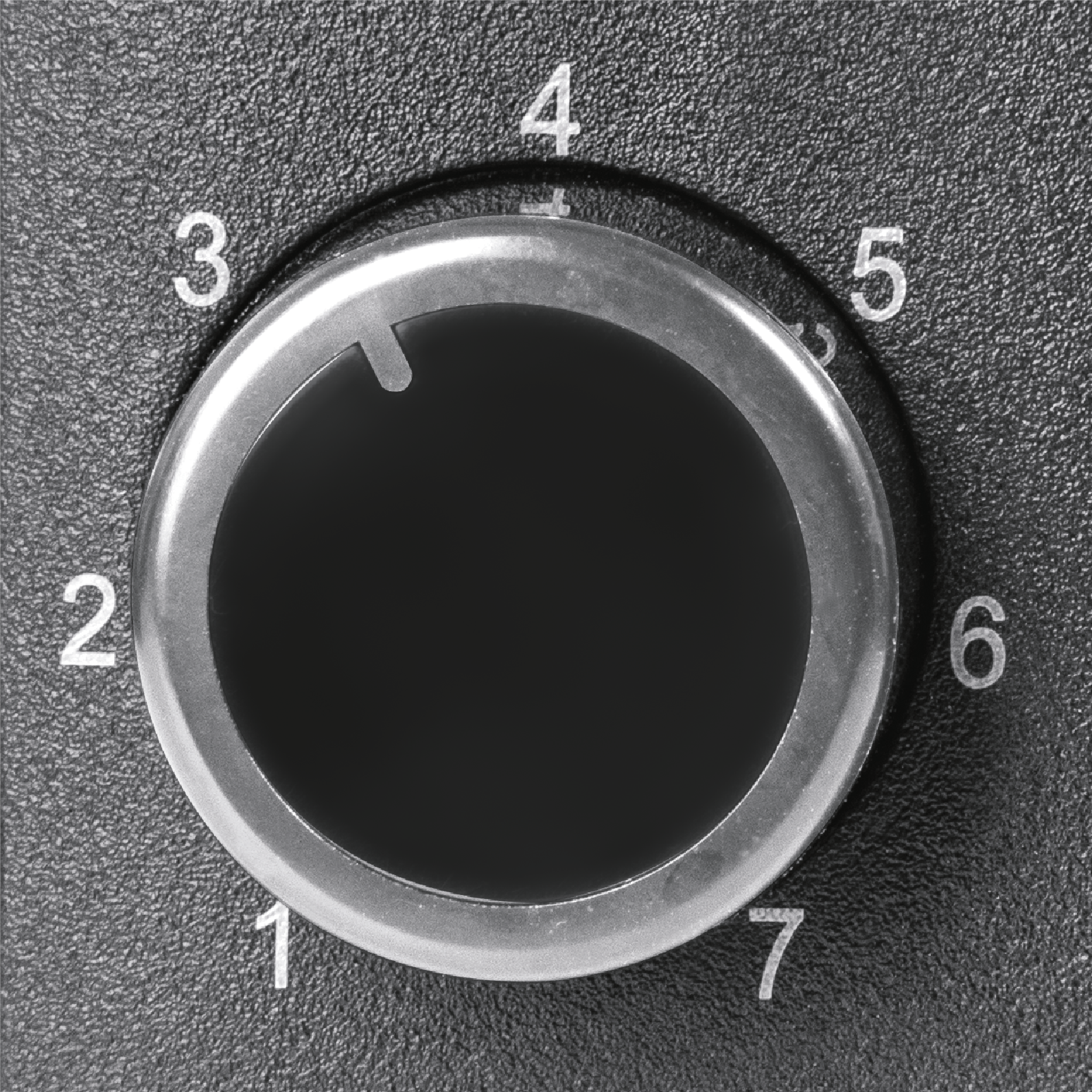 Zbliżenie czarnego pokrętła z srebrnym pierścieniem i białymi numerami od 1 do 7. Pokrętło wskazuje na 4.