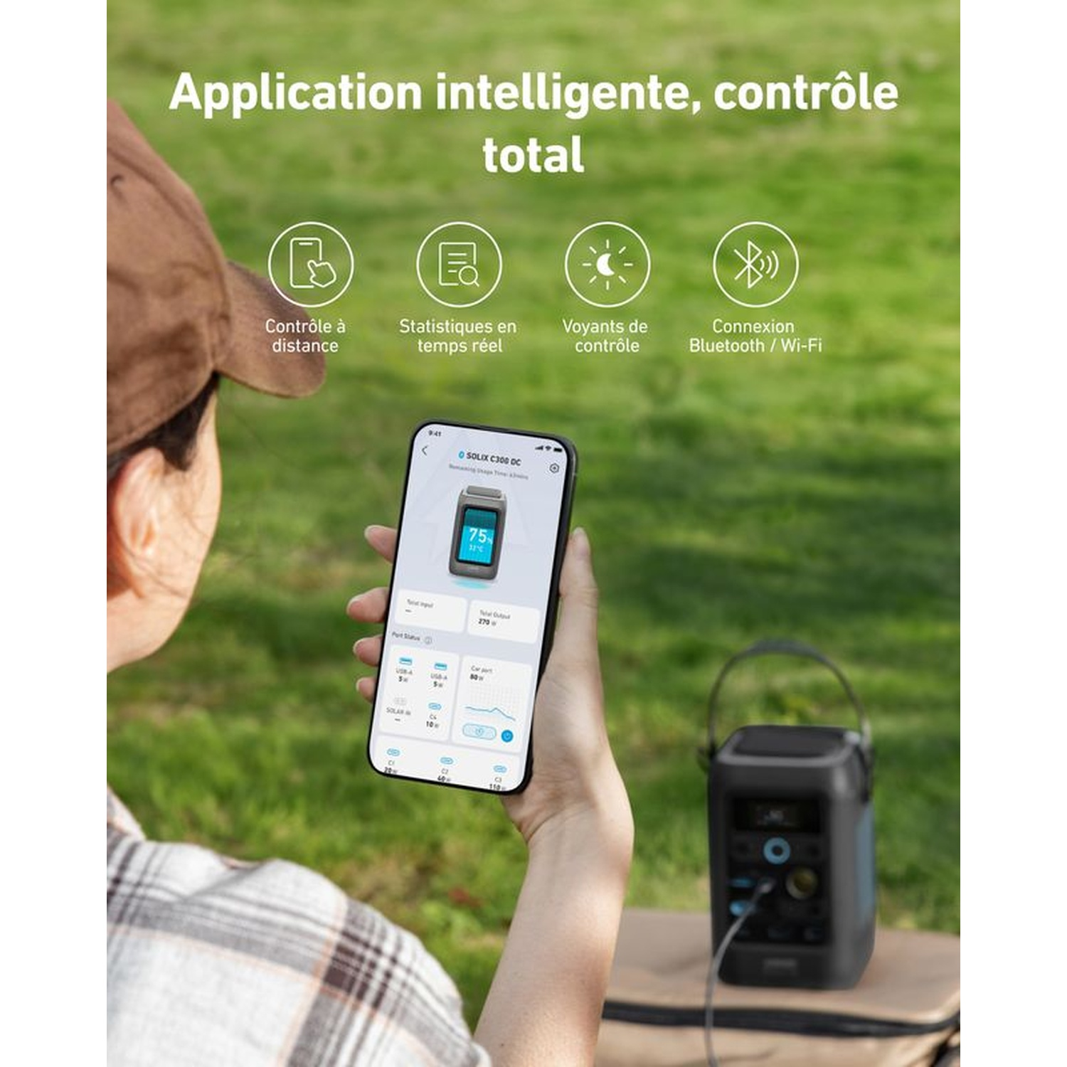 Une personne tient un téléphone montrant le contrôle de l'application d'une centrale électrique noire dans un champ vert. Texte en français.