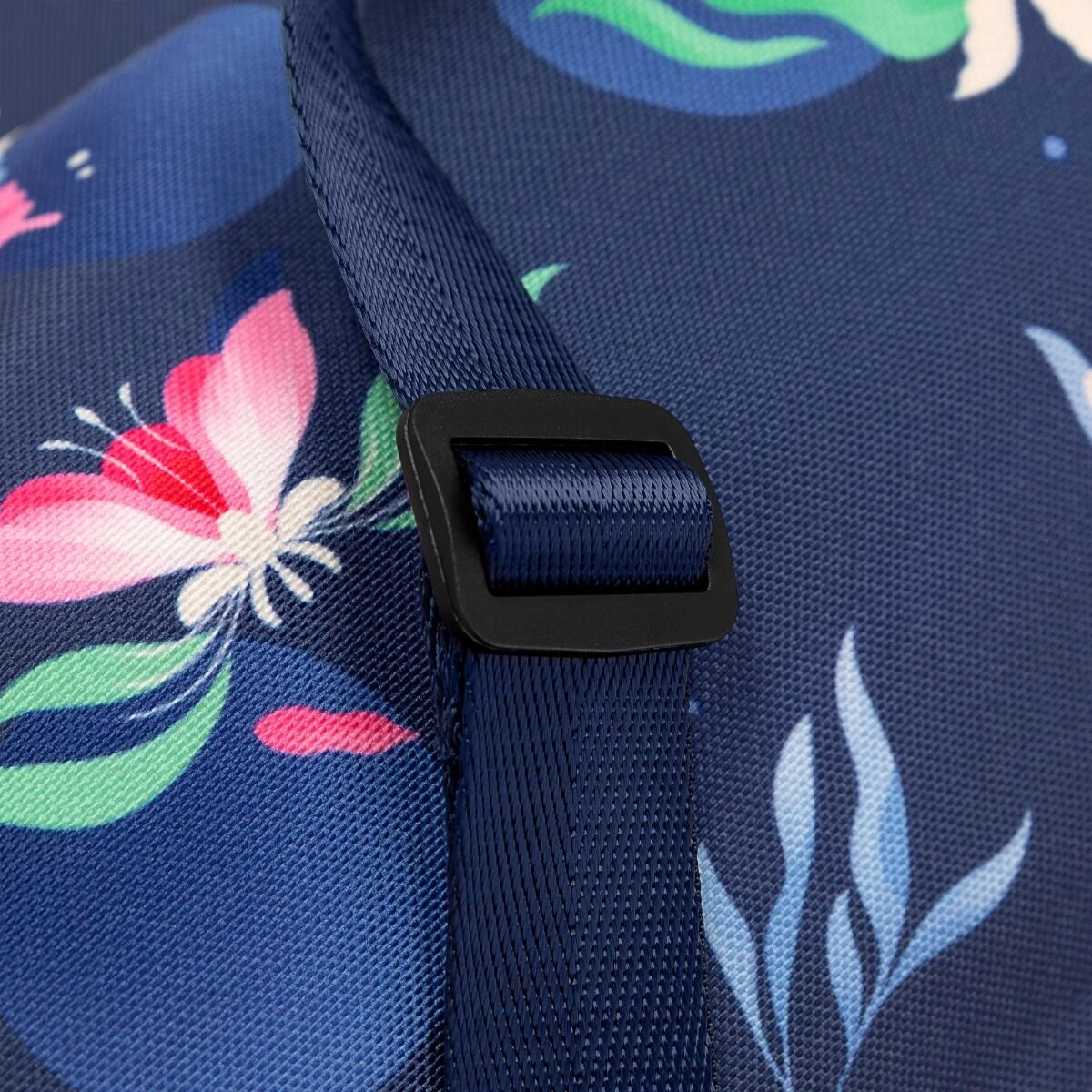 Zbliżenie wzorzystej tkaniny z paskiem i klamrą. Tkanina ma kwiatowy wzór w kolorze różowym, zielonym i białym na niebieskim tle.