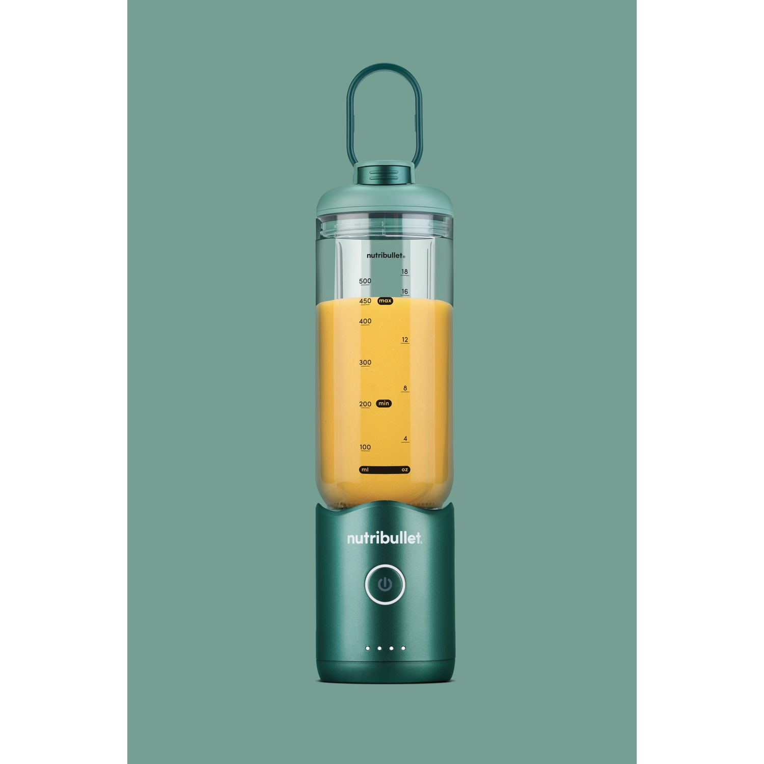 Un frullatore Nutribullet verde pieno di liquido arancione. Ha una maniglia e un pulsante di accensione, su sfondo verde acqua.
