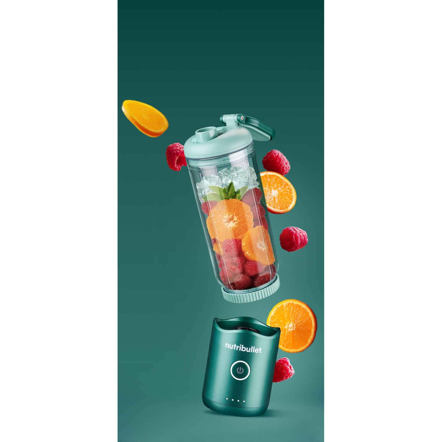 Un frullatore con frutta e ghiaccio. Fette d'arancia, lamponi e cubetti di ghiaccio sono nel frullatore. Il frullatore è verde acqua.