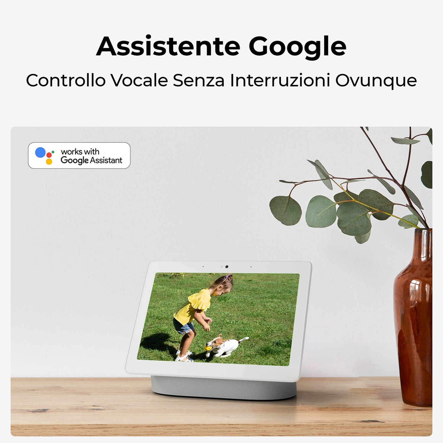 Un tablet mostra una ragazza con un cane sull'erba. Un vaso con rami è a destra. Il logo di Google Assistant è a sinistra.