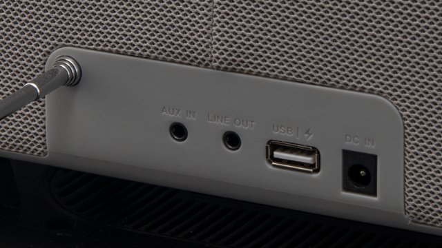 Zbliżenie tylnego panelu głośnika. Posiada porty AUX IN, LINE OUT, USB i DC IN. Kabel jest podłączony do portu AUX IN.