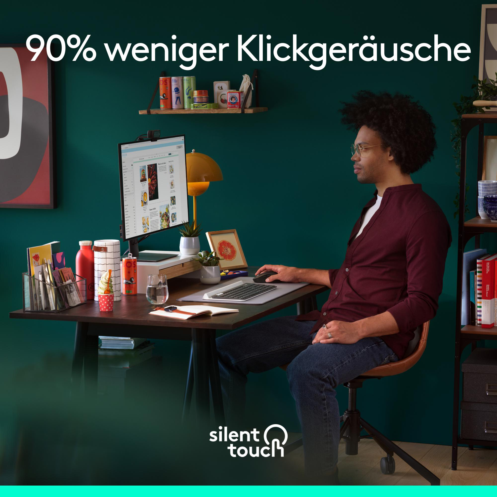 Mann arbeitet an einem Schreibtisch mit Computer. Auf dem Schreibtisch befinden sich Pflanzen und ein Wasserglas.