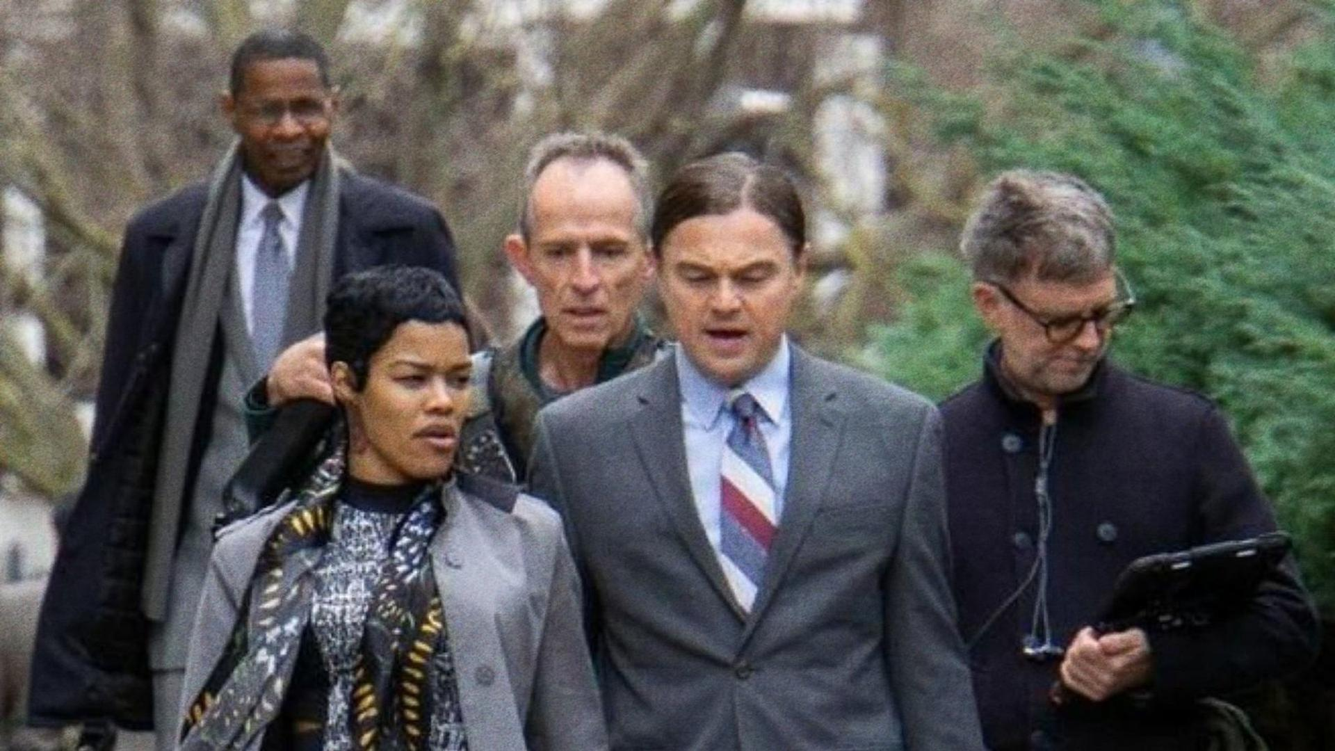 Eine Gruppe von Leuten, darunter Leonardo DiCaprio, geht draußen. Sie sind von Bäumen und einem verschwommenen Hintergrund umgeben.