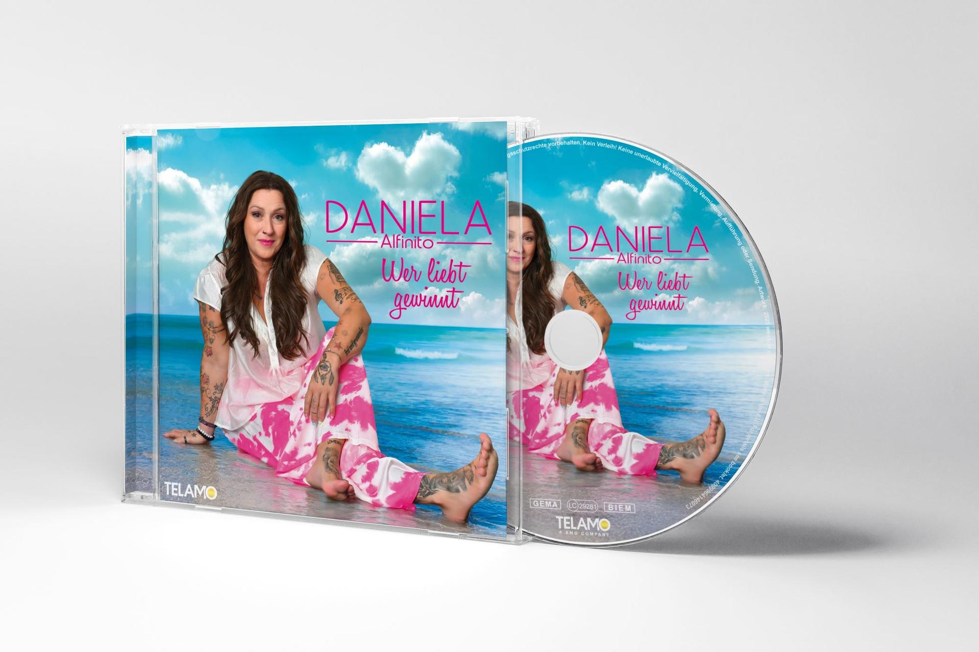 CD-Cover von Daniela Alfinito, Album 'Wer liebt gewinnt'. Sie trägt eine rosa Hose und ein weißes Oberteil. Himmelshintergrund.
