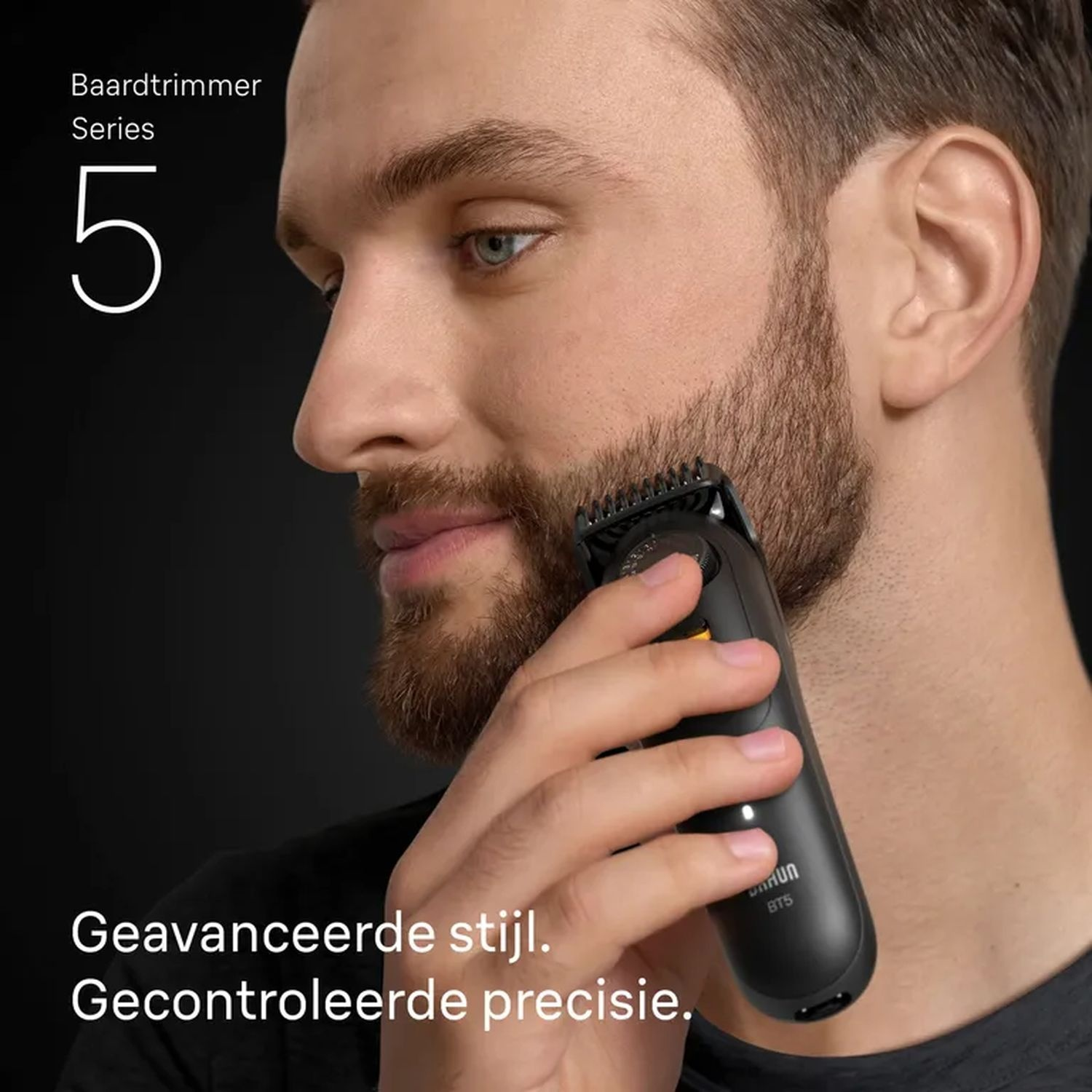 A man shaves his beard with a black trimmer. The trimmer is close to his beard. Text: Baardtrimmer Series 5.