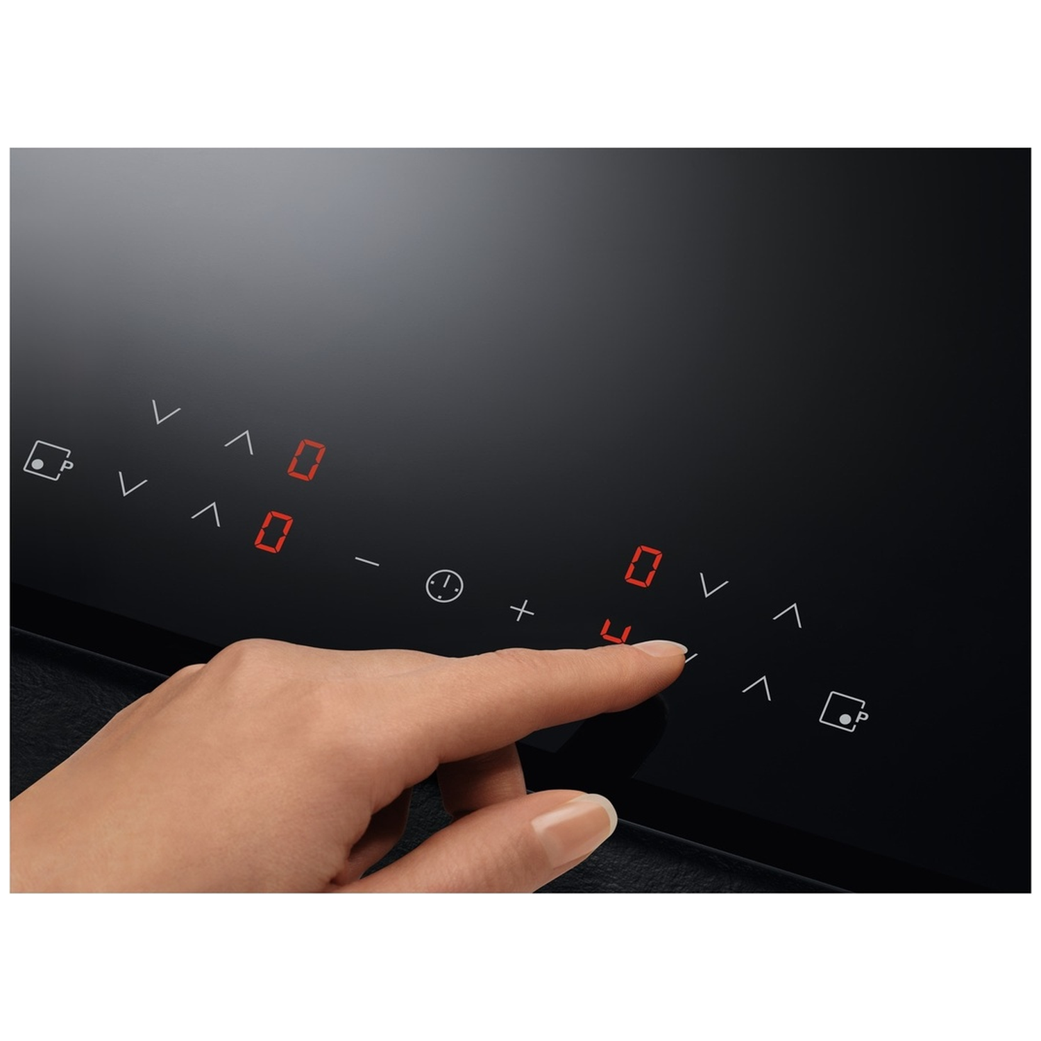 A hand is touching a black induction cooktop. Red numbers and symbols are displayed. The touch panel is visible.