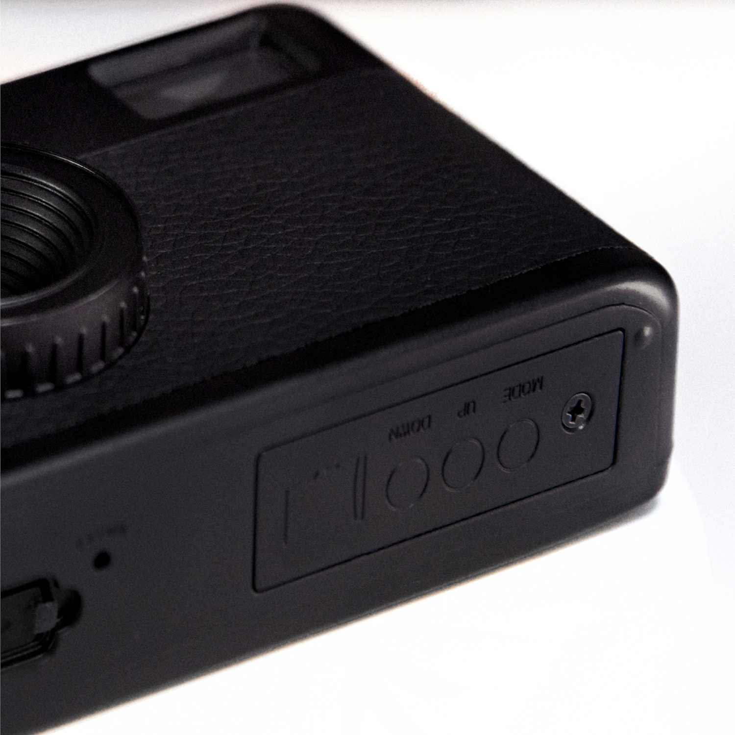 Close-up of a black camera body. Showing lens, textured leather, and control buttons.