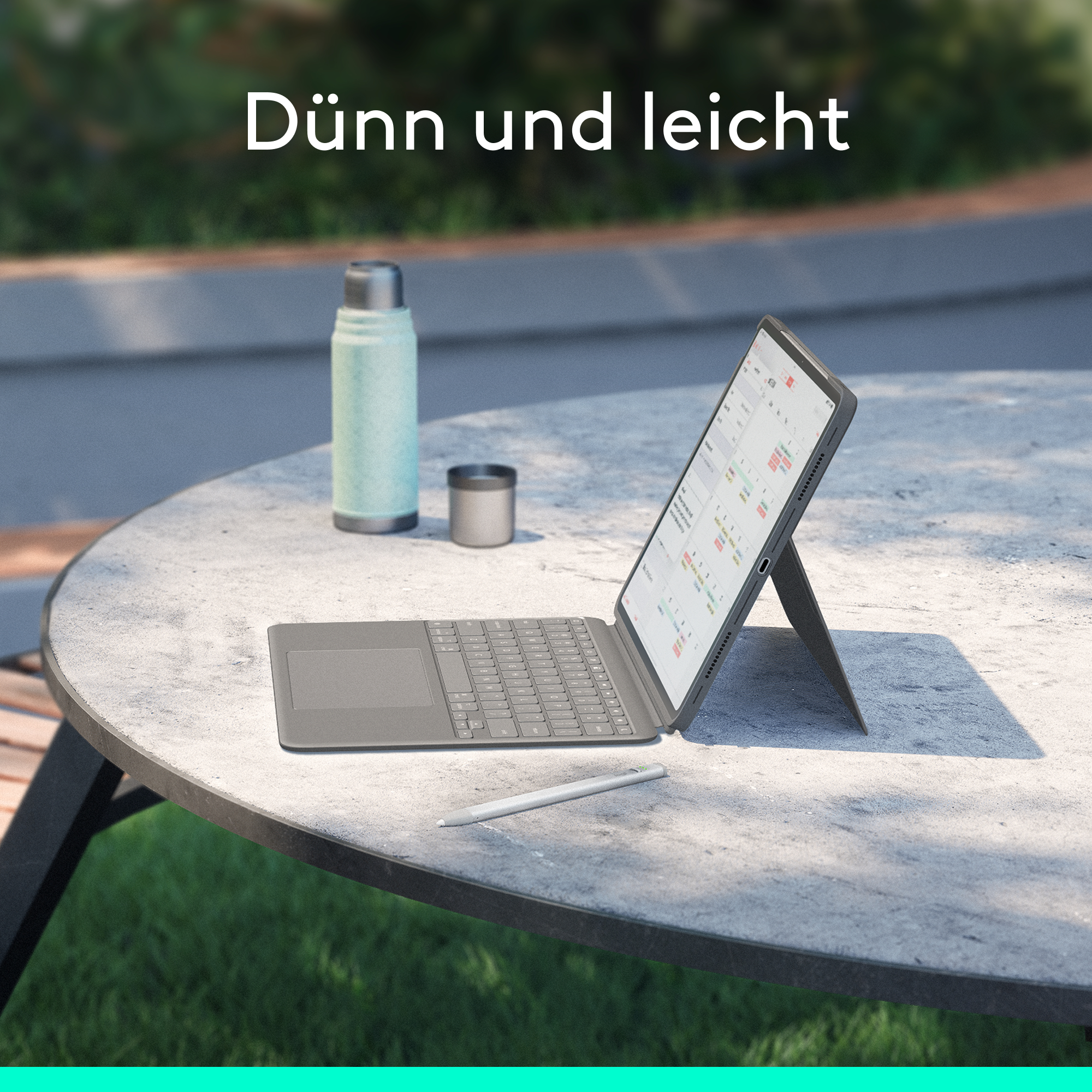 Tablet mit Tastatur auf einem Tisch, neben einer Flasche und einer Tasse.