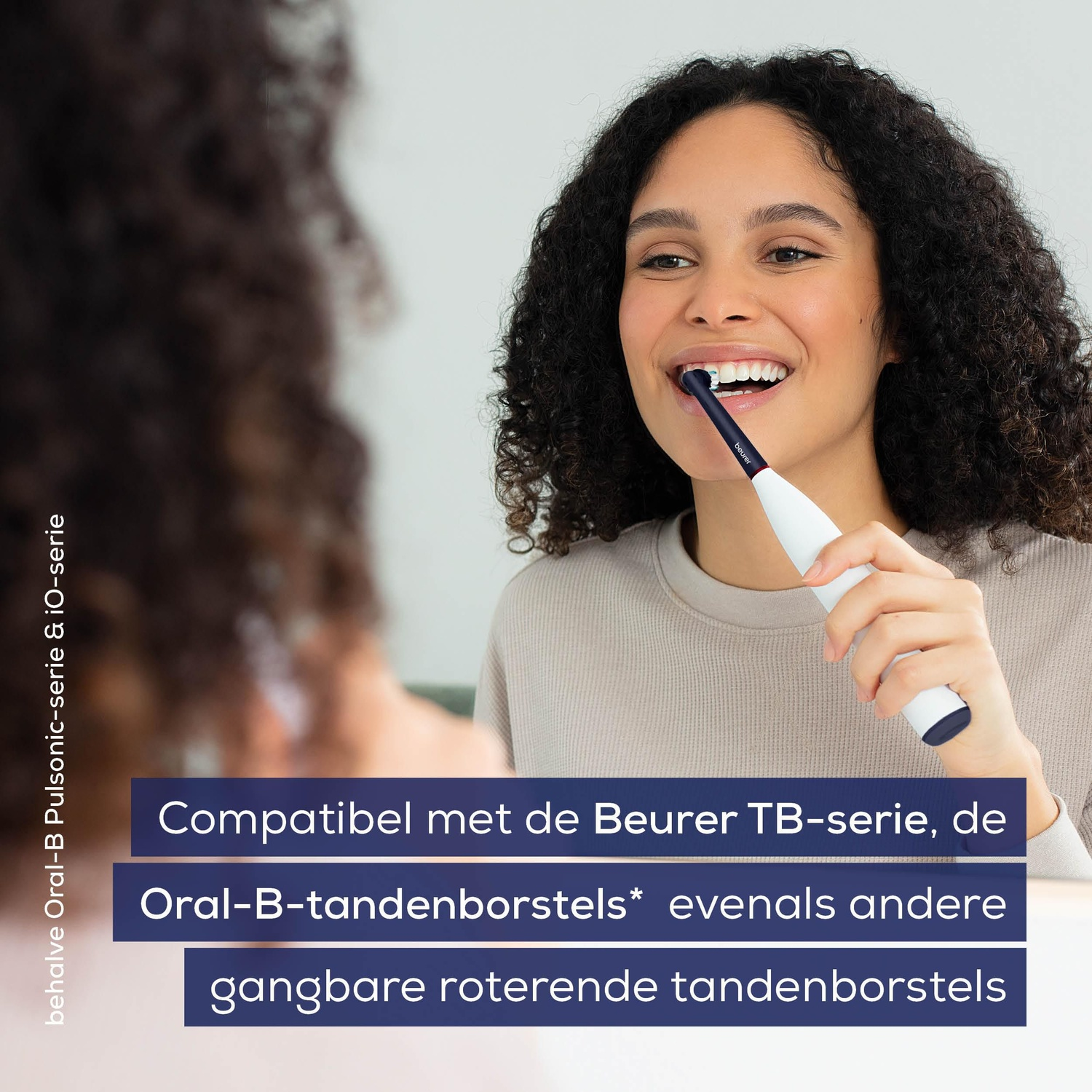 Een vrouw poetst haar tanden met een witte en blauwe elektrische tandenborstel en glimlacht. Onderstaande tekst geeft compatibiliteit met de Oral-B-serie aan.