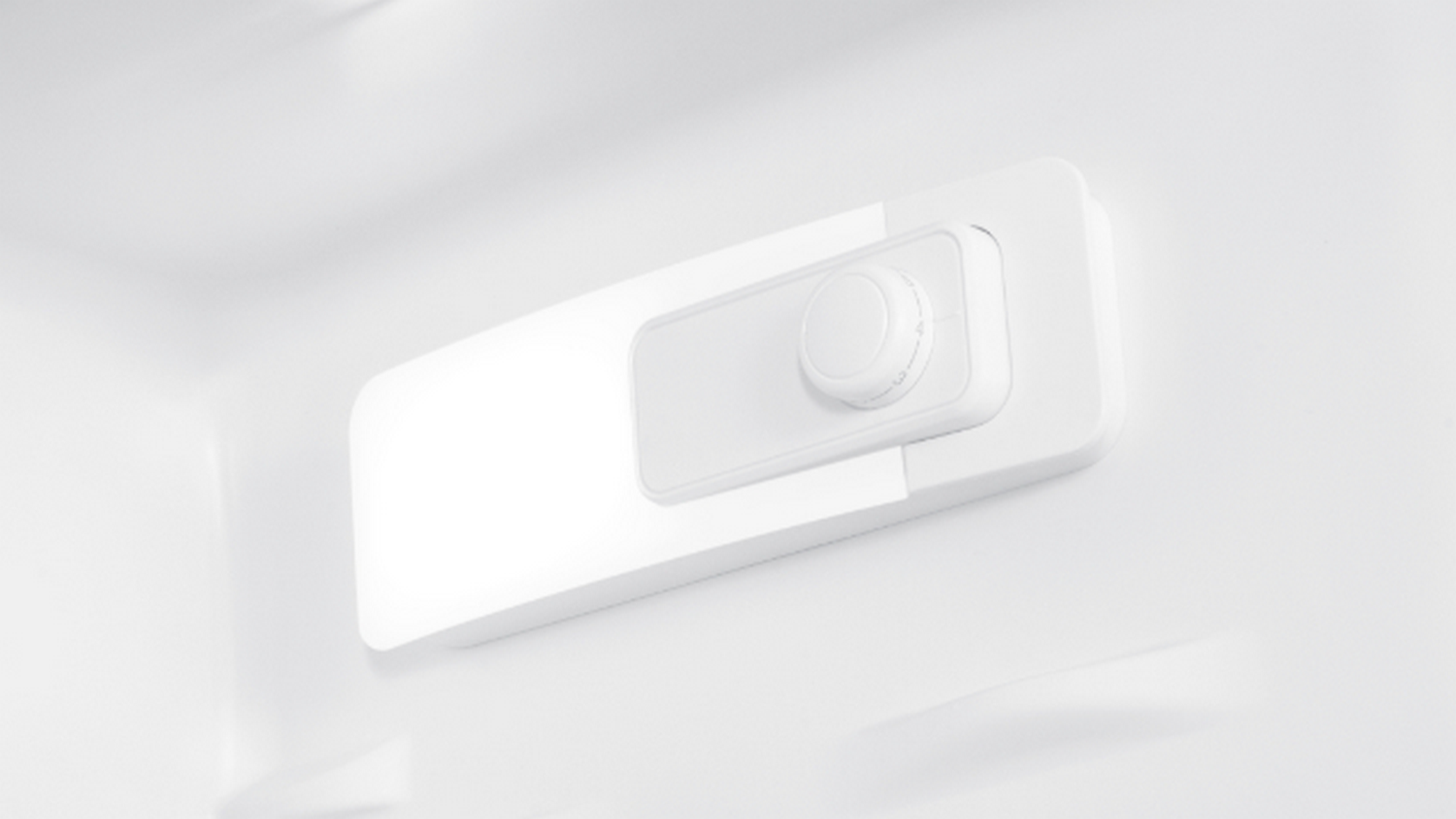 Dentro de un refrigerador blanco, se ve un panel de control blanco con una perilla. Tiene forma rectangular redondeada.
