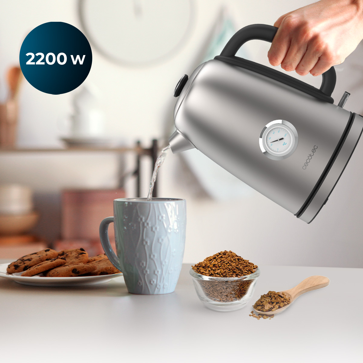 Una persona vierte agua de una tetera plateada en una taza azul claro. Hay café molido y galletas en la mesa.