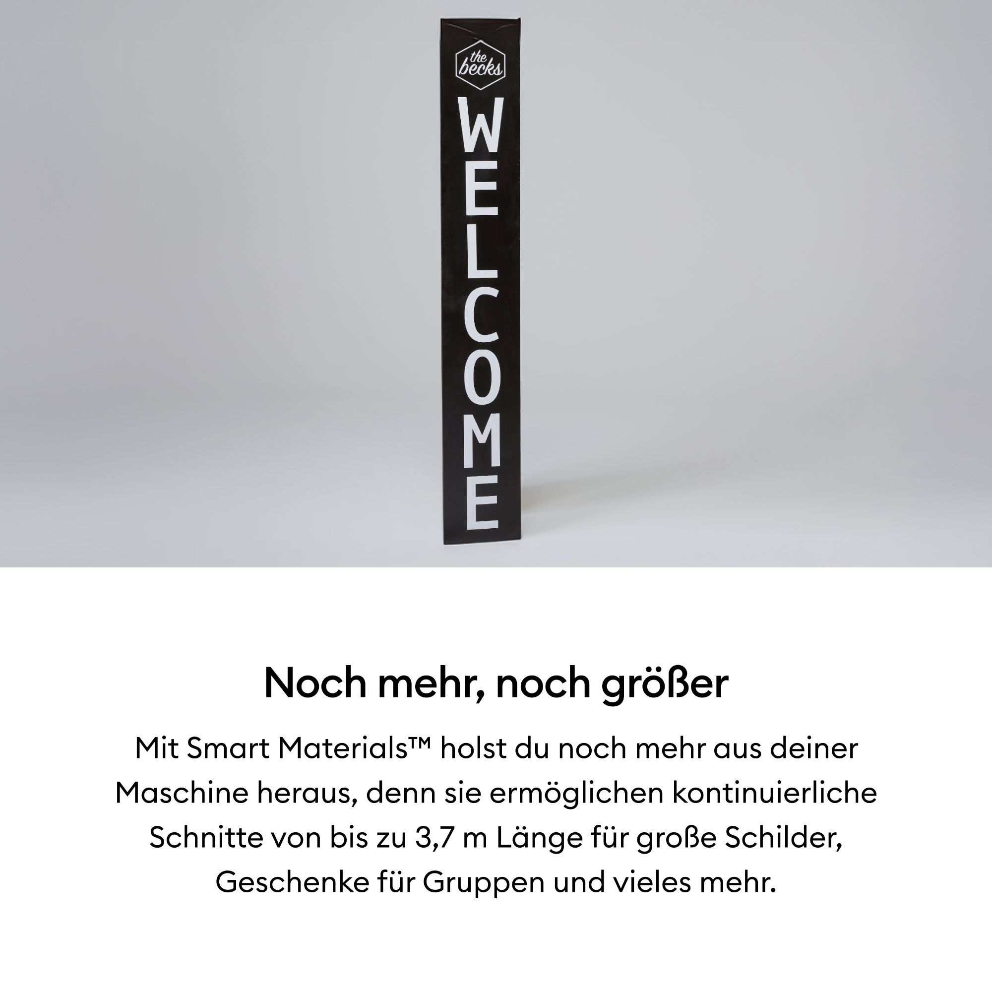 Ein schwarzes Willkommensschild mit weißen Buchstaben. Es steht senkrecht vor einem hellgrauen Hintergrund. Das Schild sagt 'WELCOME'.