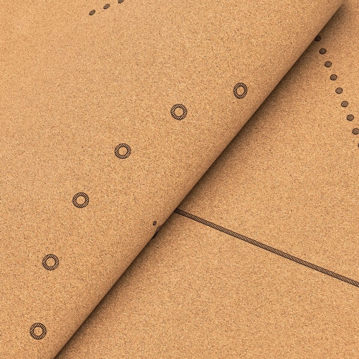 Zbliżenie brązowego materiału korkowego. Ma okrągłe i liniowe wzory. Materiał jest częściowo zwinięty, ukazując kilka warstw.