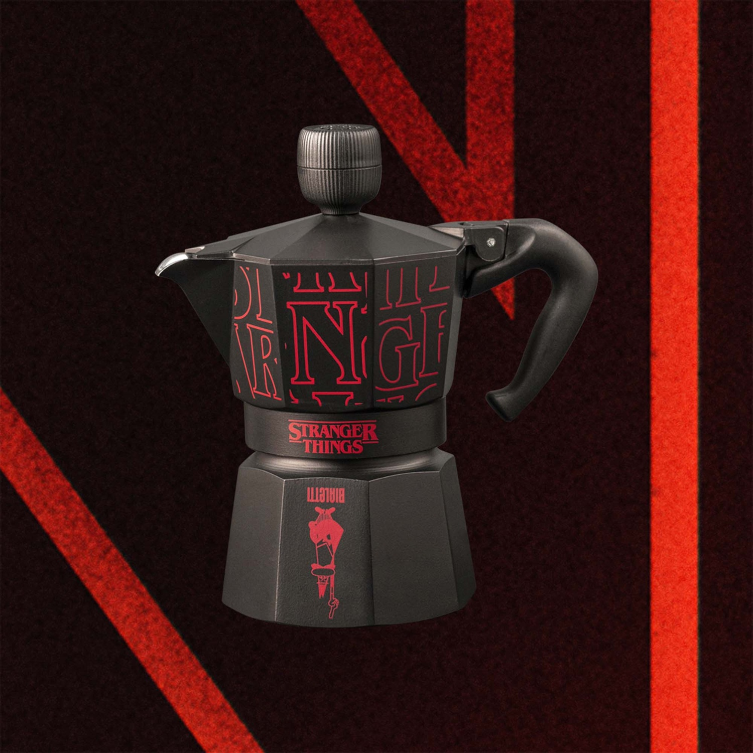 Macchina da caffè nera con logo rosso Stranger Things. Linee rosse su sfondo rosso scuro.