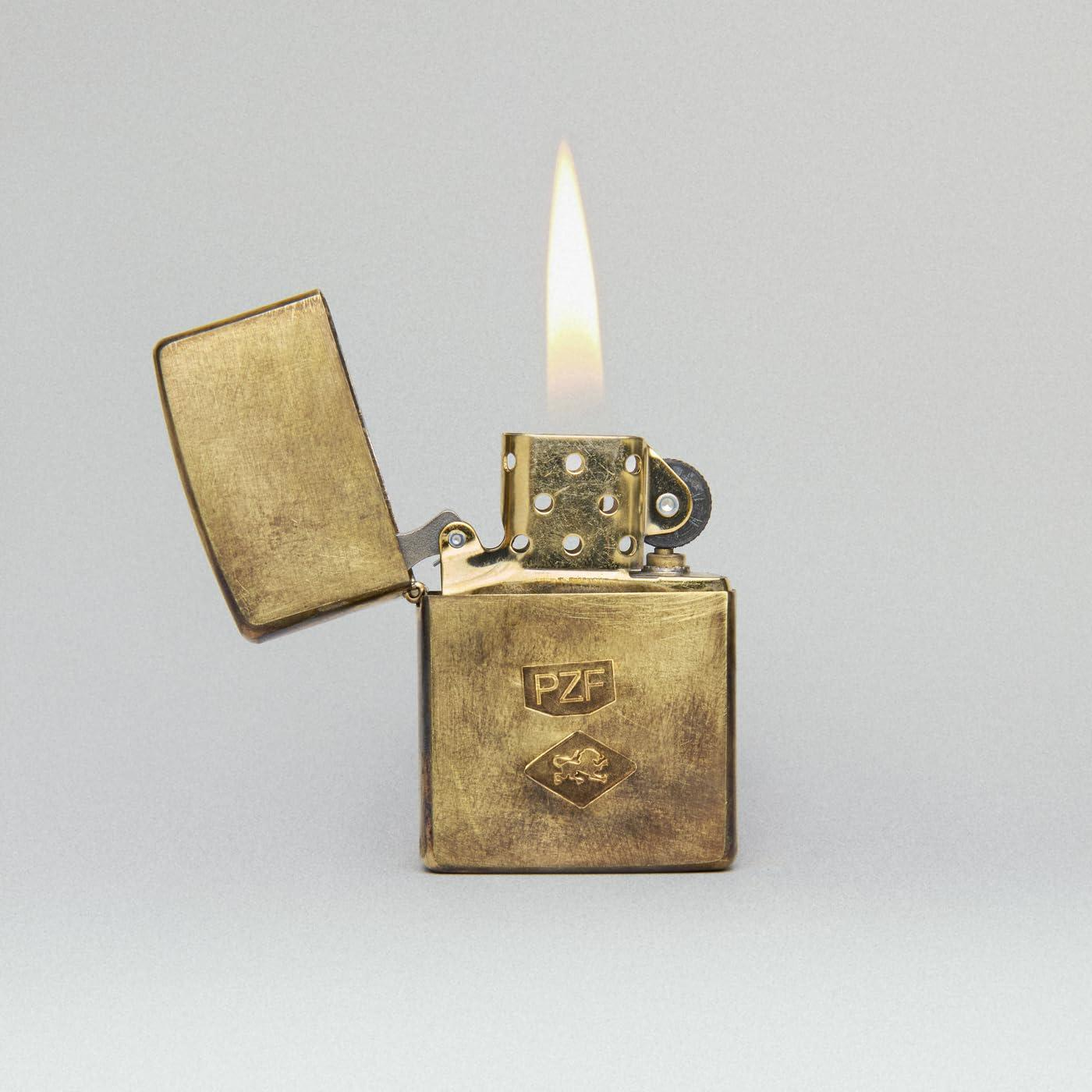 Een vintage gouden aansteker met een open deksel, een vlam brandt, op een grijze achtergrond.
