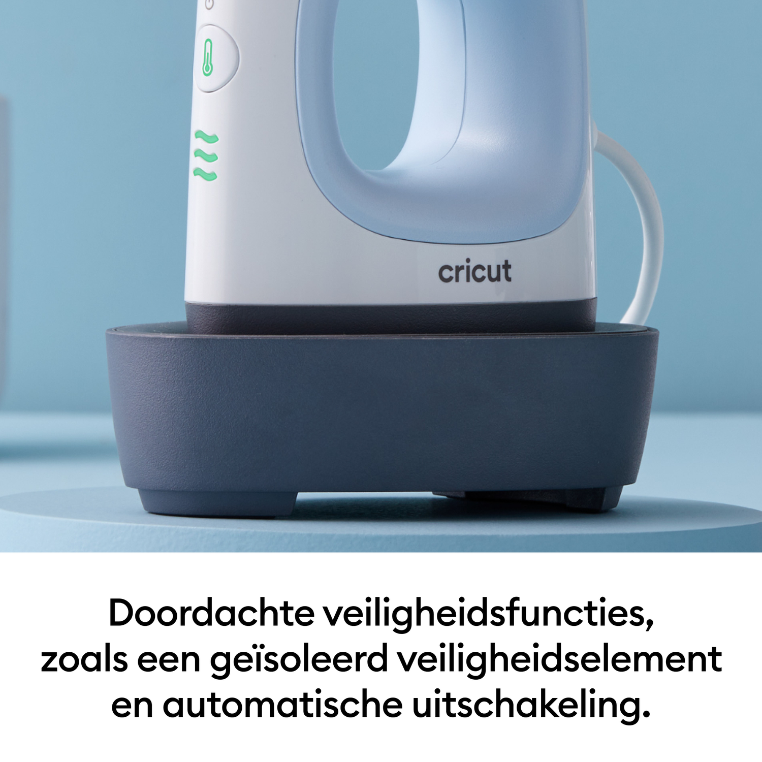 A white and blue Cricut iron with a handle, resting on a dark blue base, against a light blue backdrop.