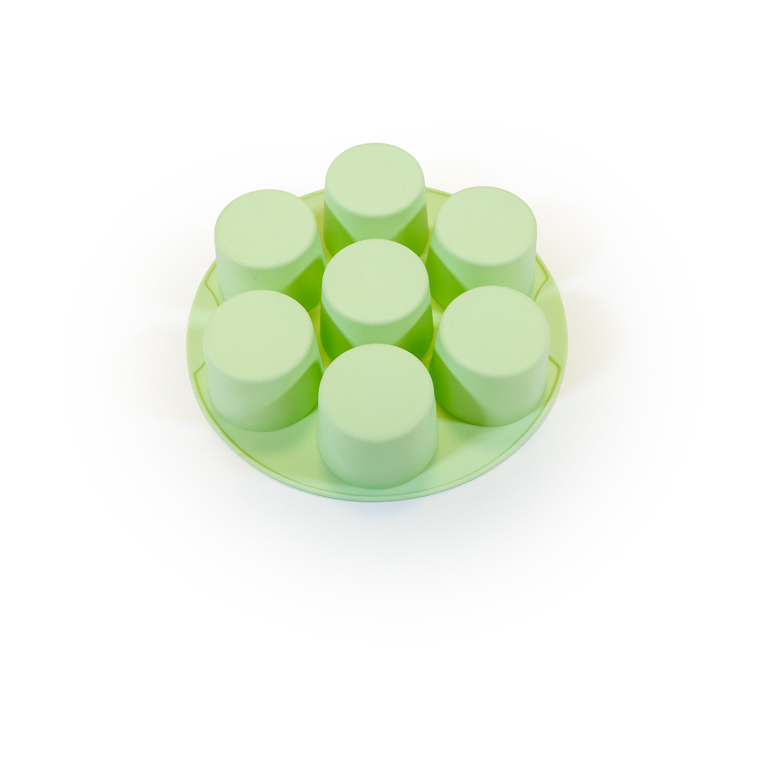 Uno stampo in silicone verde chiaro con sette cavità cilindriche su sfondo bianco. Lo stampo è circolare.