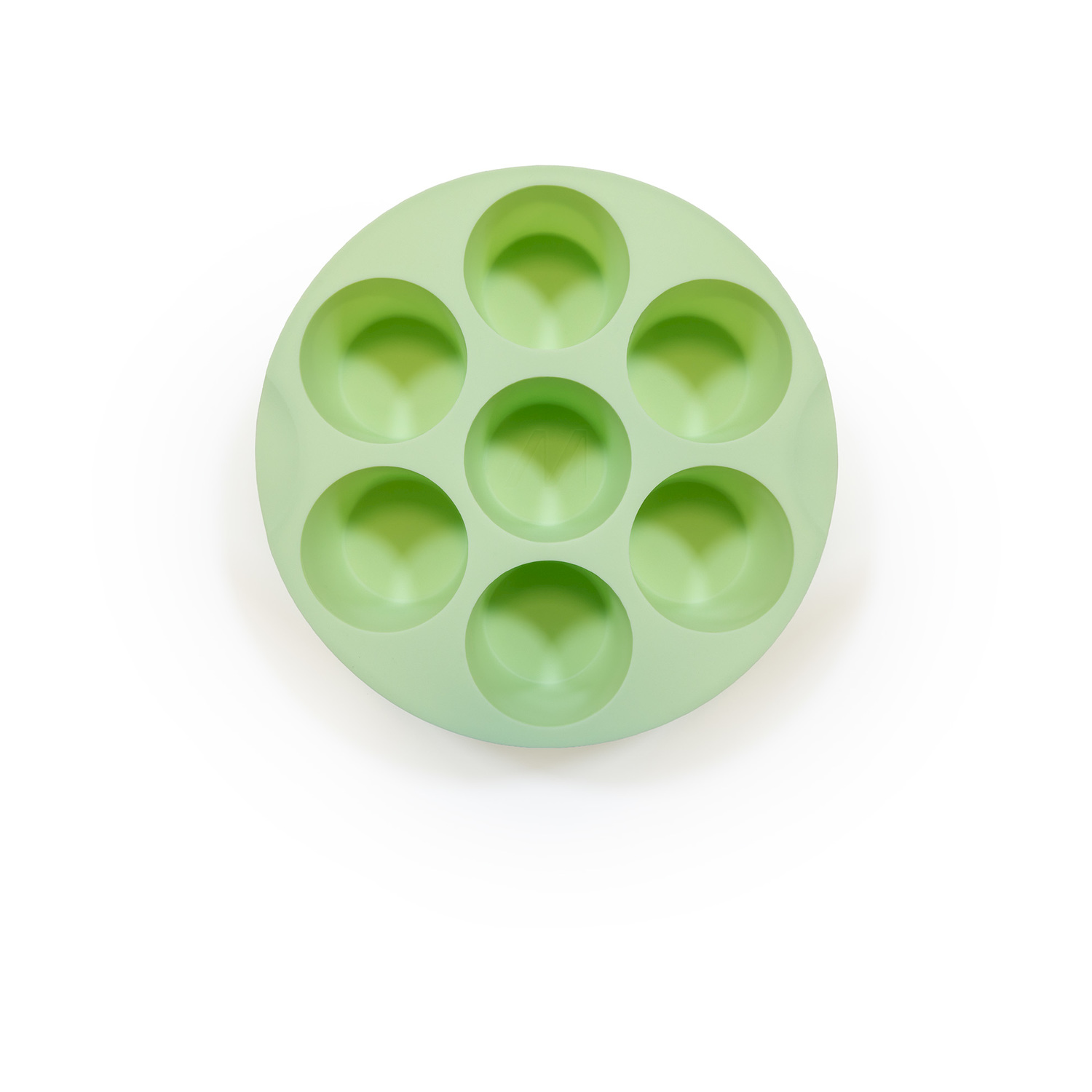 Uno stampo circolare in silicone verde chiaro con sette cavità rotonde. Si trova su uno sfondo bianco. Lo stampo è visto dall'alto.