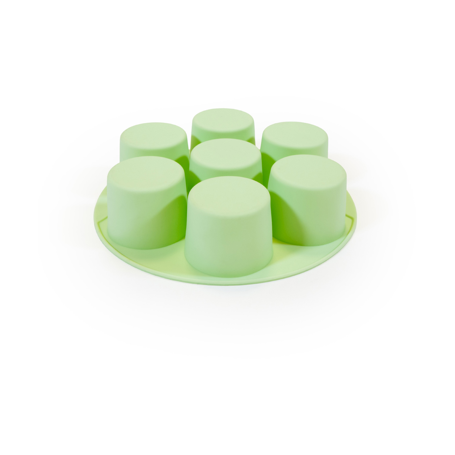 Uno stampo in silicone verde chiaro con sette tazze cilindriche. Lo stampo è su una superficie bianca.